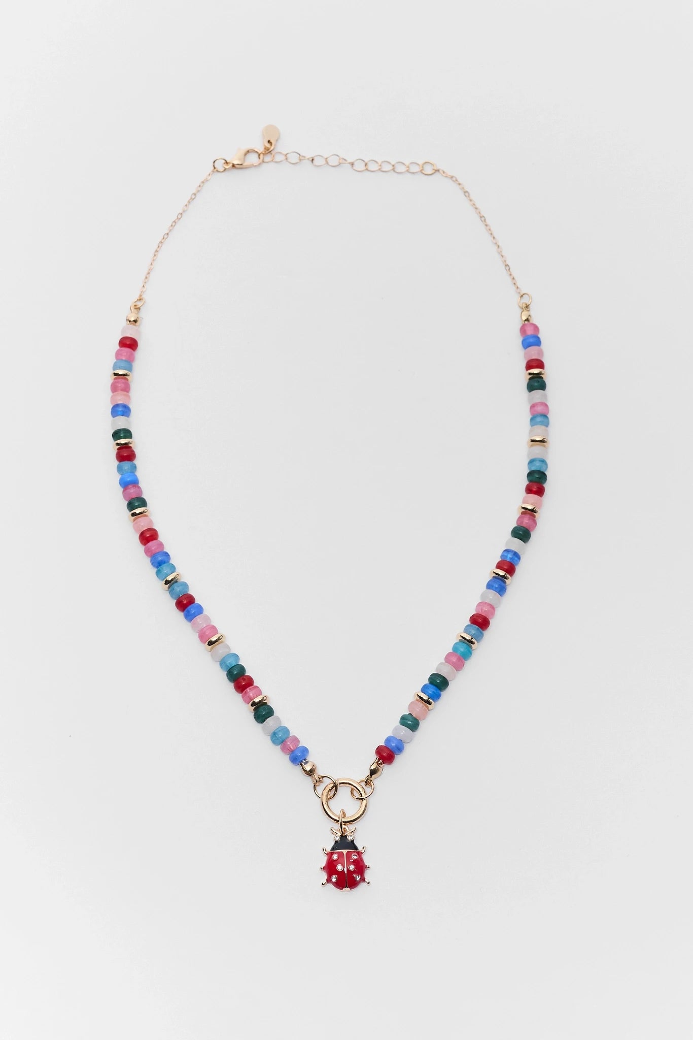 Multicolored beaded necklace with a small red ladybug pendant on a white background