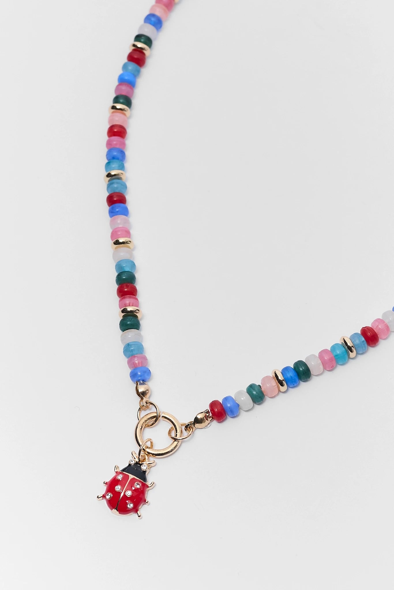 Colorful beaded necklace with a ladybug charm on a white background close up