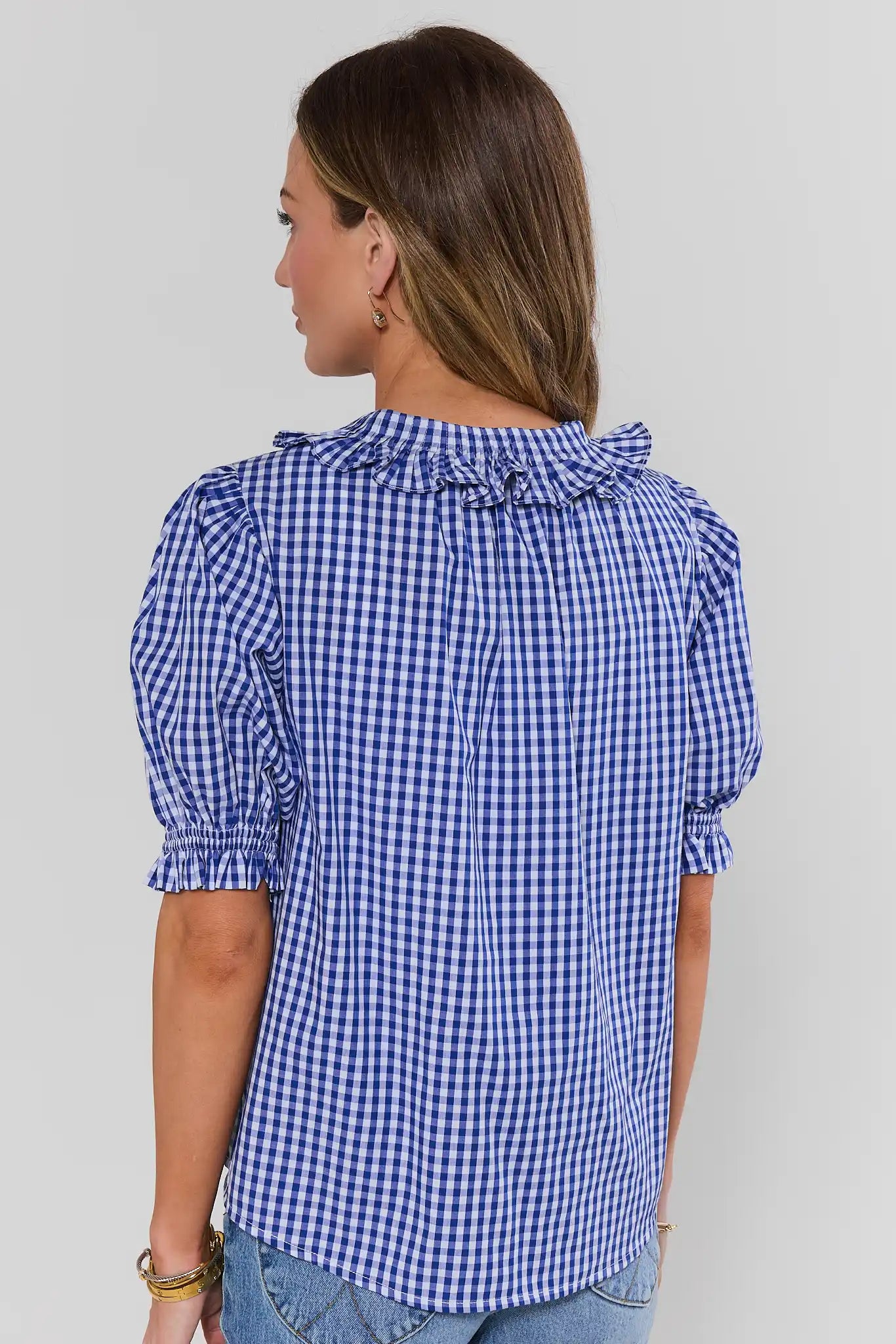 Woman wearing a blue checkered blouse against a plain background standing