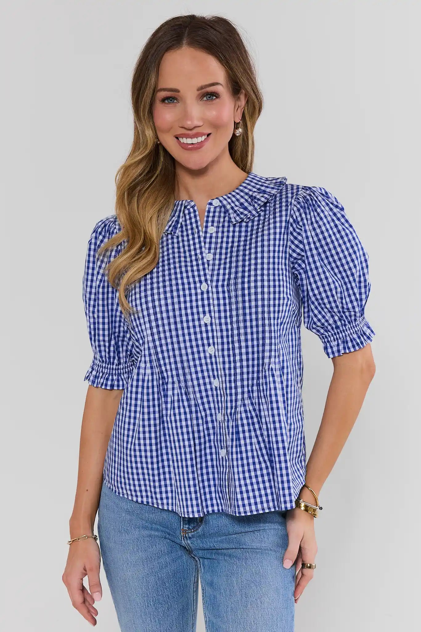 Woman wearing a blue checkered blouse with puff sleeves against a plain background