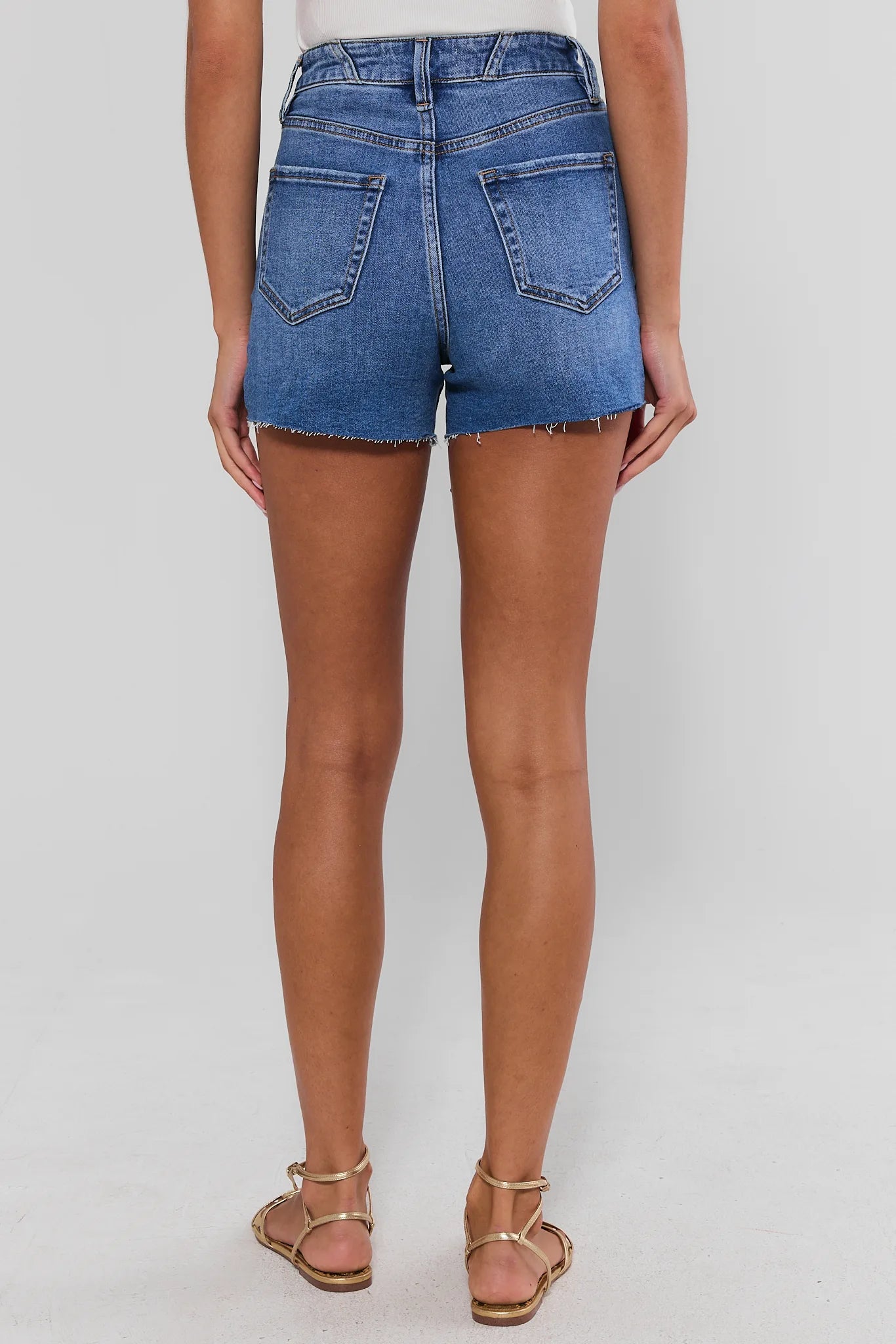 woman wearing medium wash shorts on white background standing