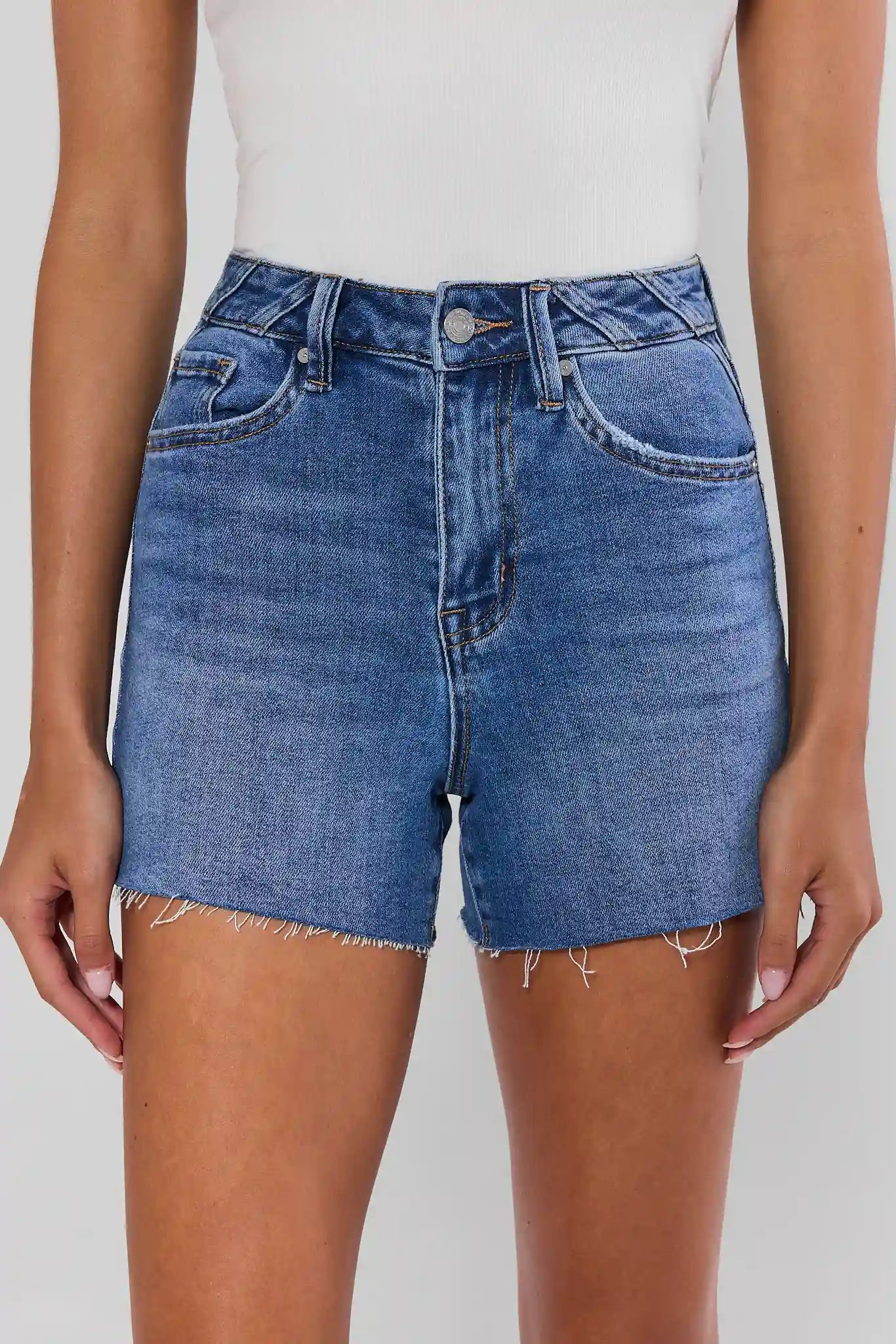 woman wearing medium wash shorts on white background