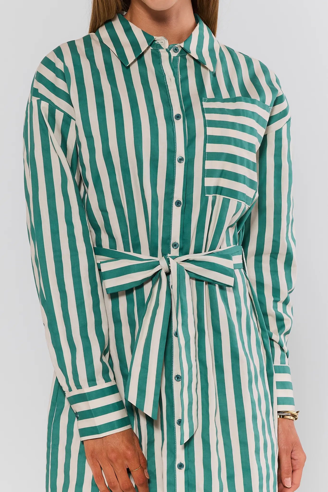 Green and white striped shirt dress worn by a person on a plain background close up