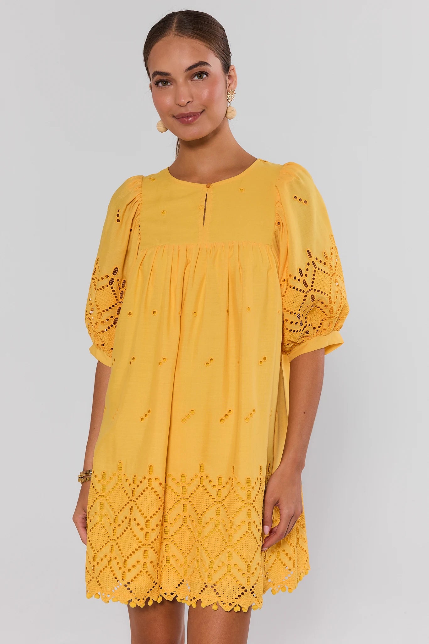 Woman wearing a yellow dress with lace details on a white background