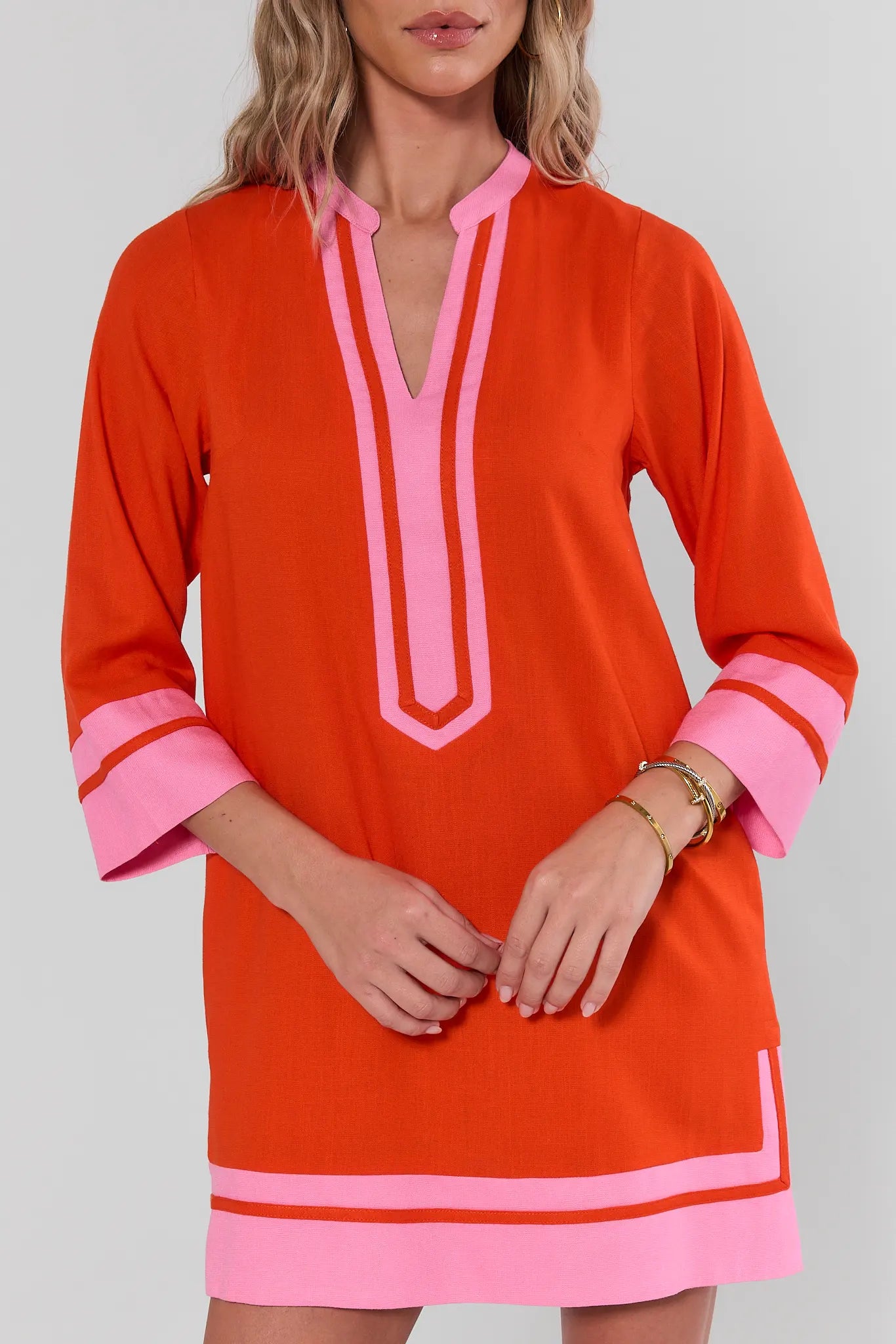 Orange dress with pink accents worn by a model on a plain background close up