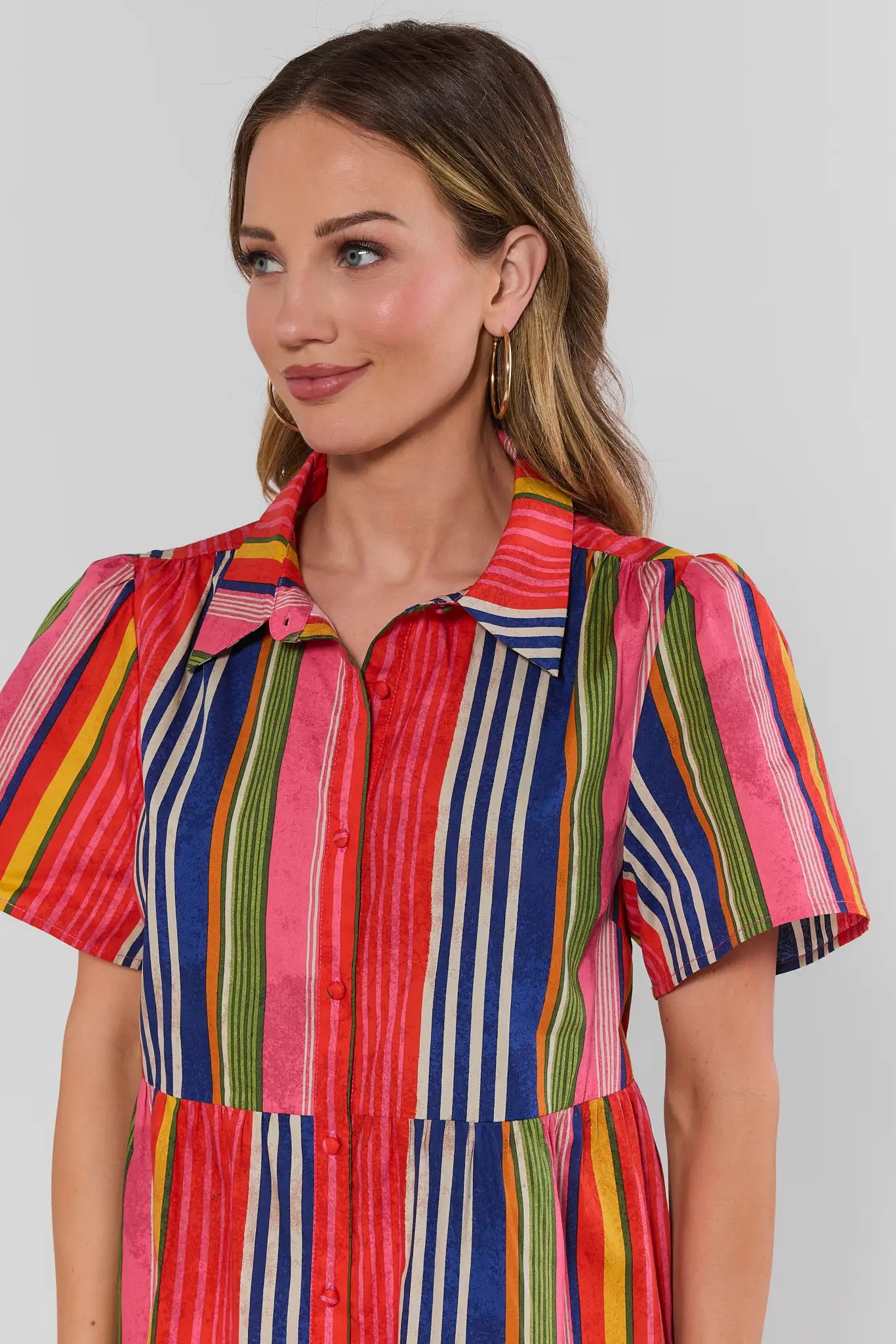 Woman wearing a colorful striped dress against a plain background close up