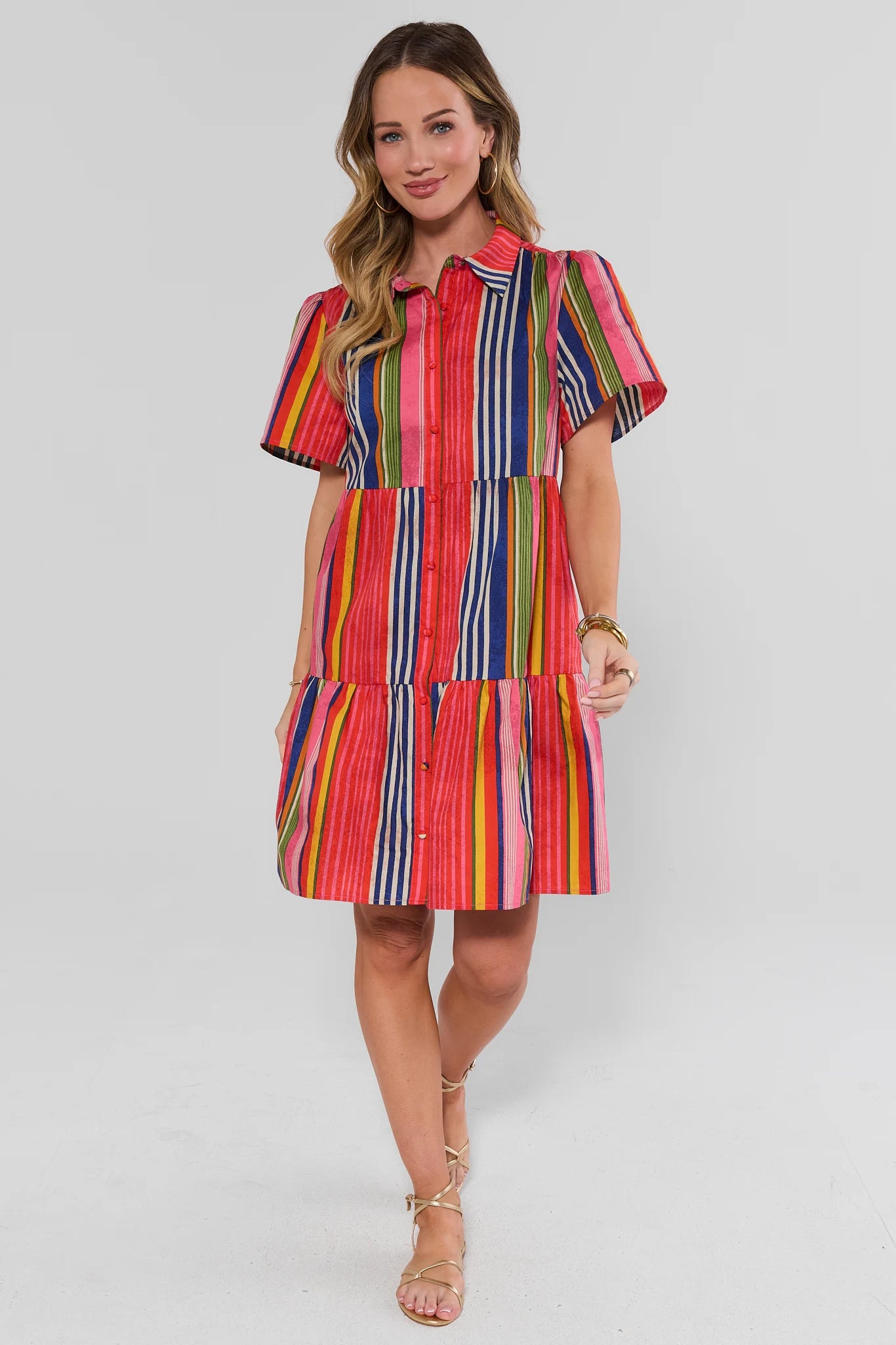 Woman standing wearing a colorful striped dress on a white background