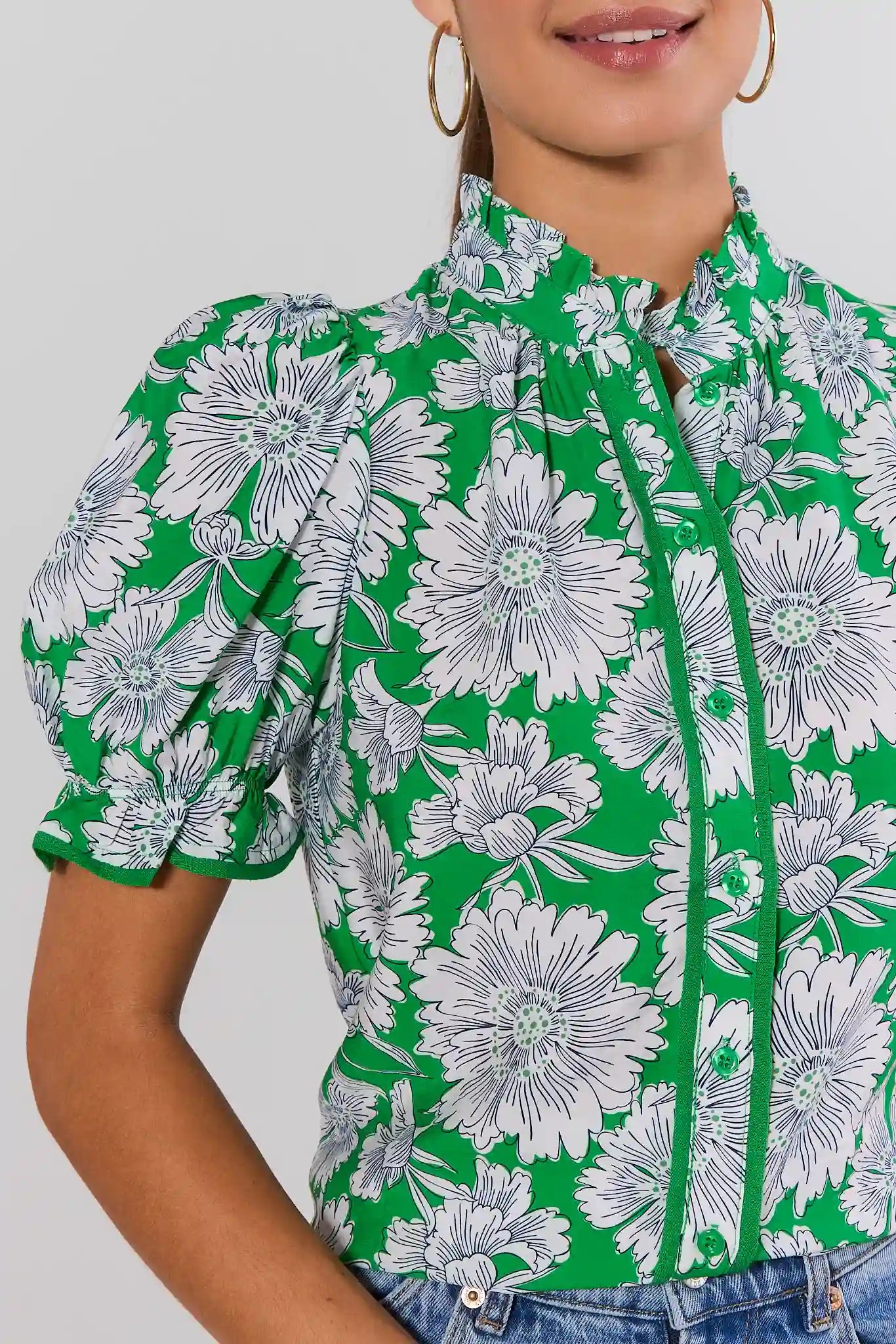 close up Green floral blouse worn by a person on a plain background