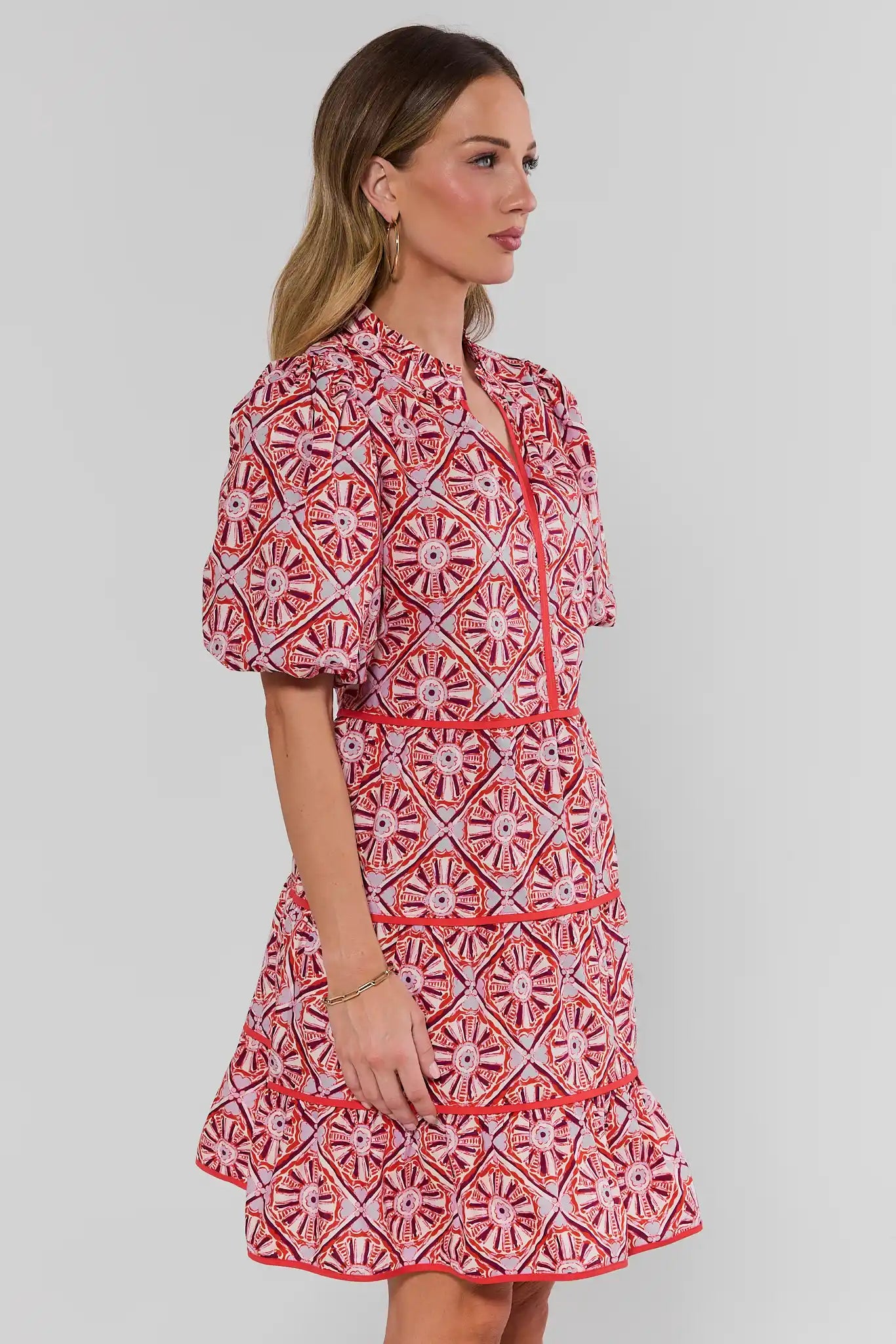 Woman wearing a red and white patterned dress on a plain background side