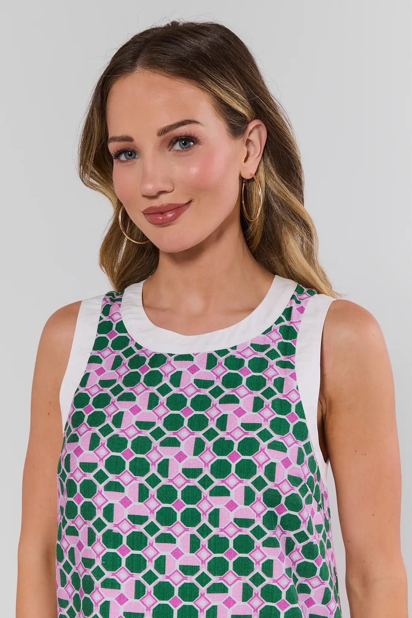 Woman wearing a sleeveless dress with a geometric pattern on a plain background close up