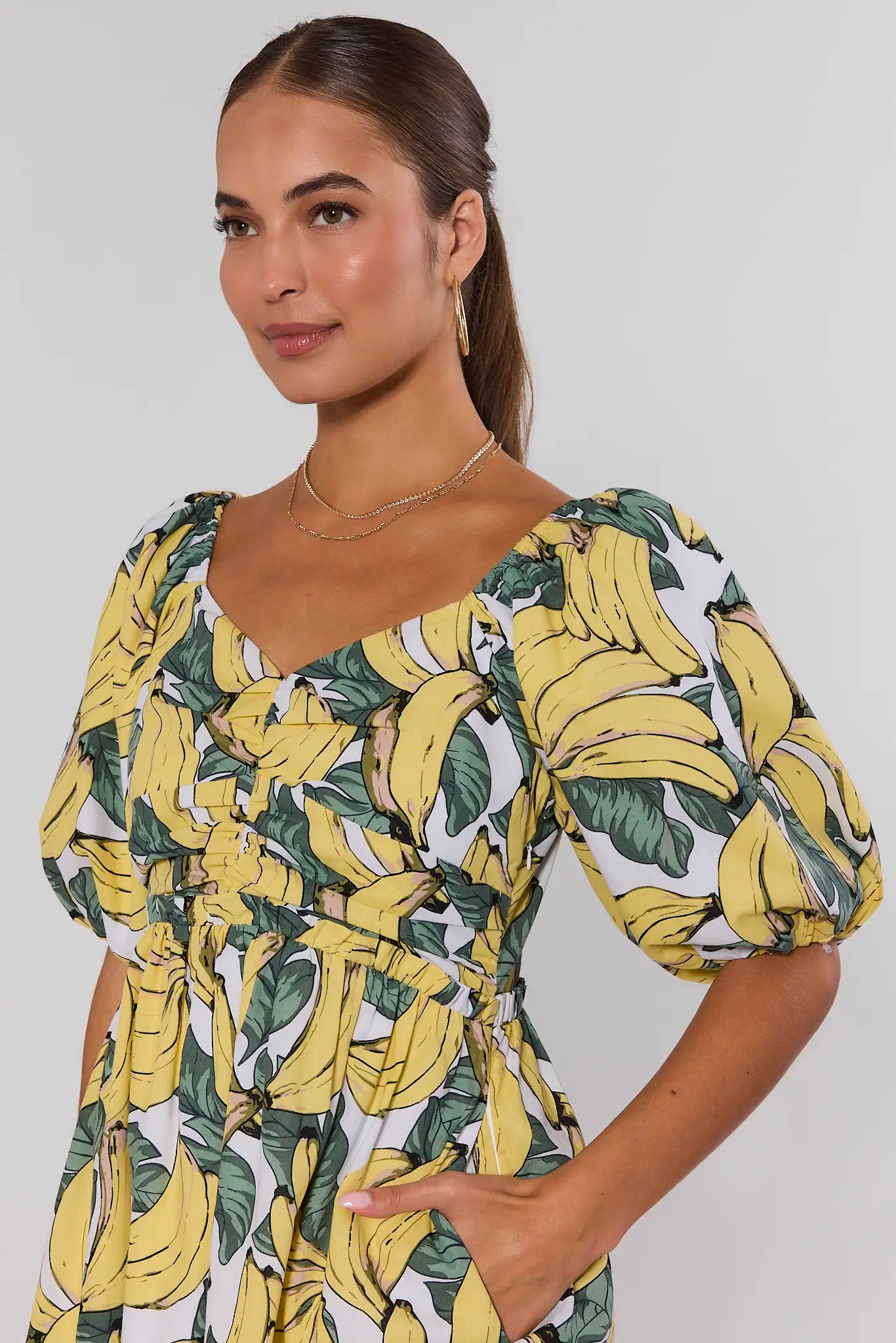 Woman wearing a dress with banana leaf pattern against a plain background close up