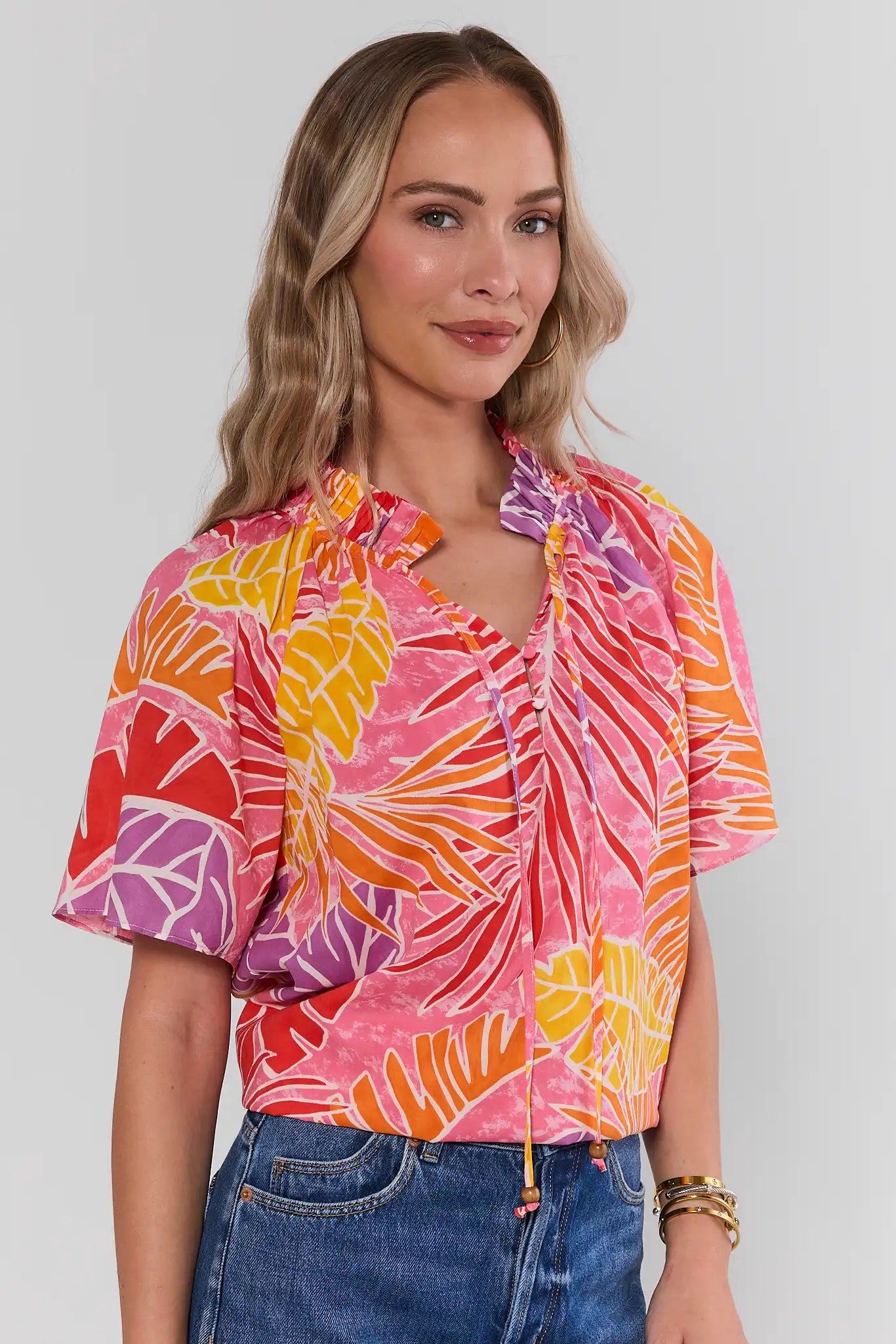 Woman wearing a colorful patterned blouse with a plain background side