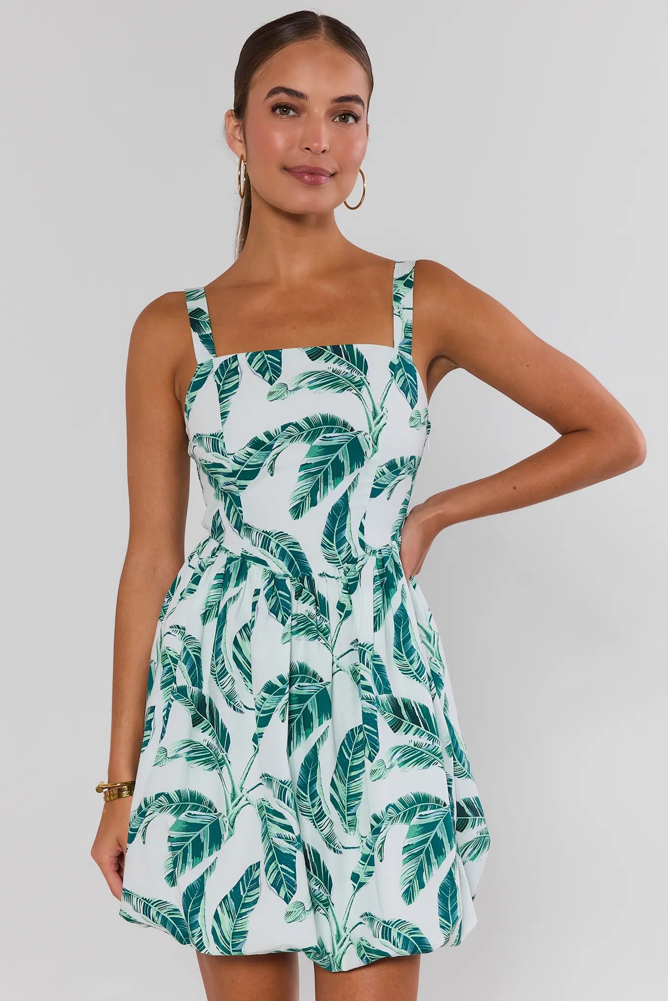 Woman wearing a green leaf patterned dress on a white background
