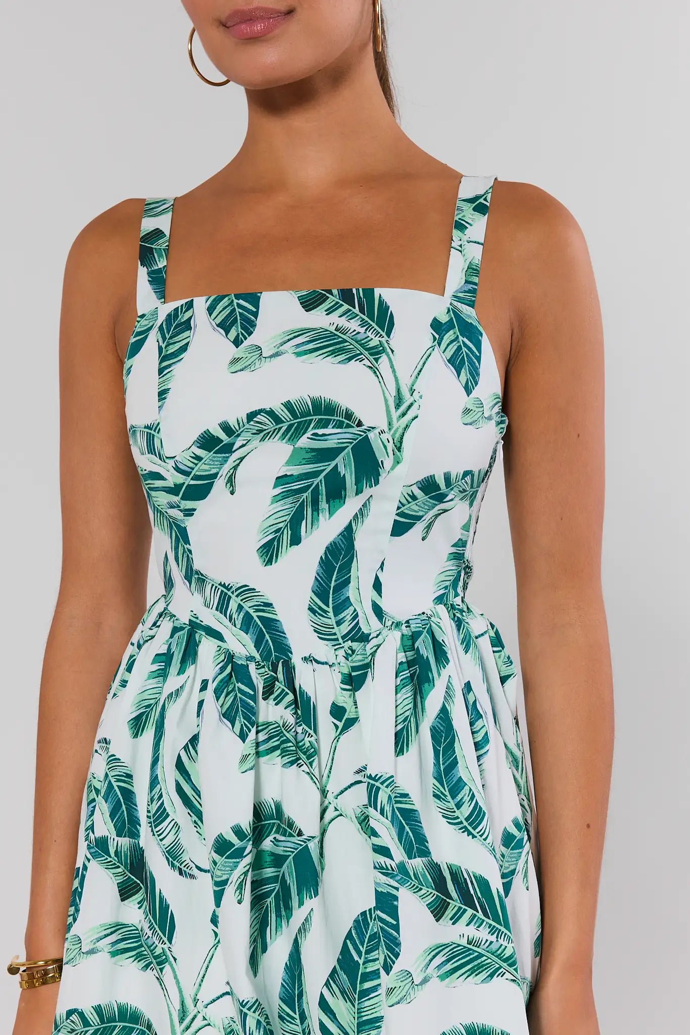 Woman wearing a dress with green leaf pattern on a plain background close up