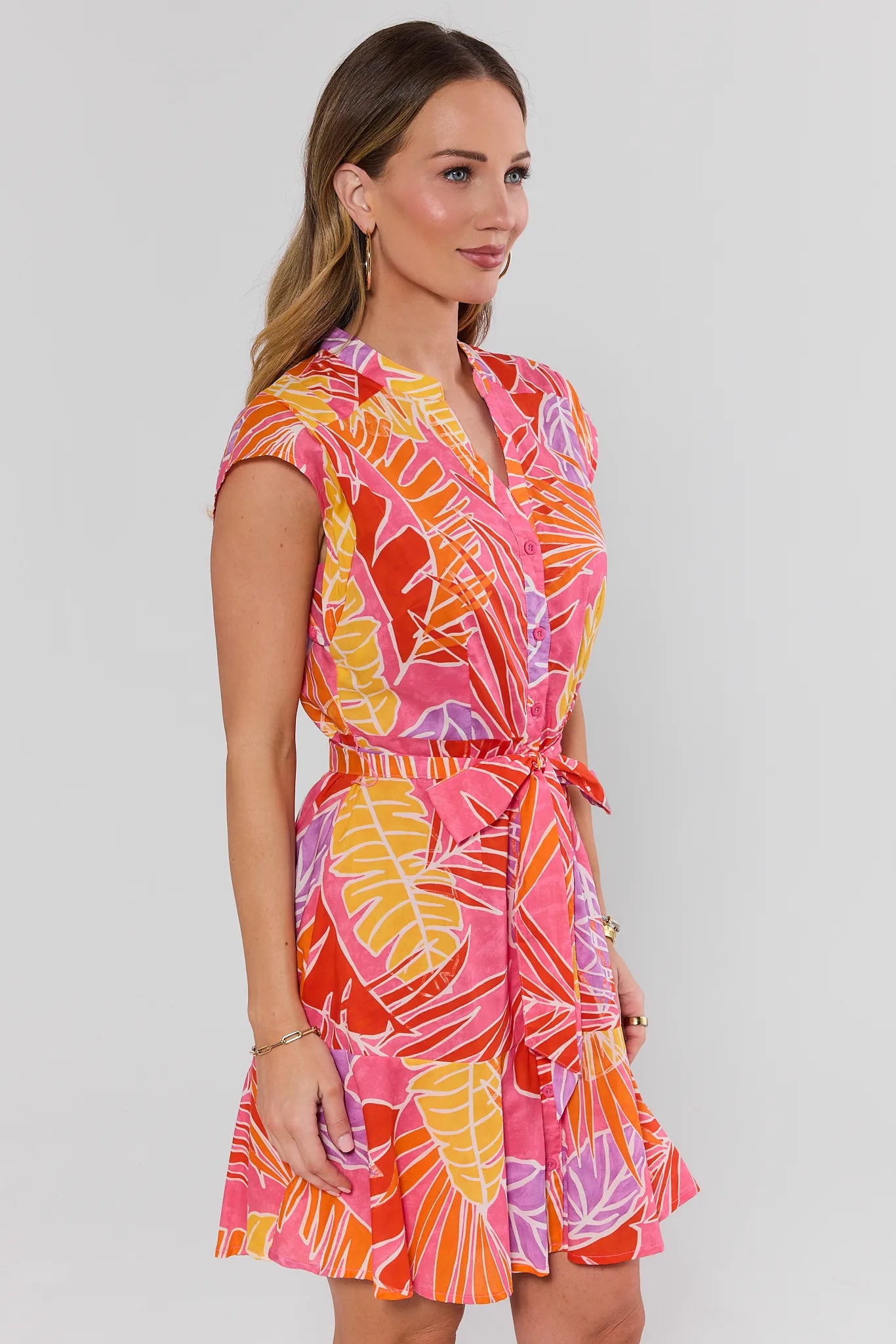 Woman wearing a colorful patterned dress on a plain background side