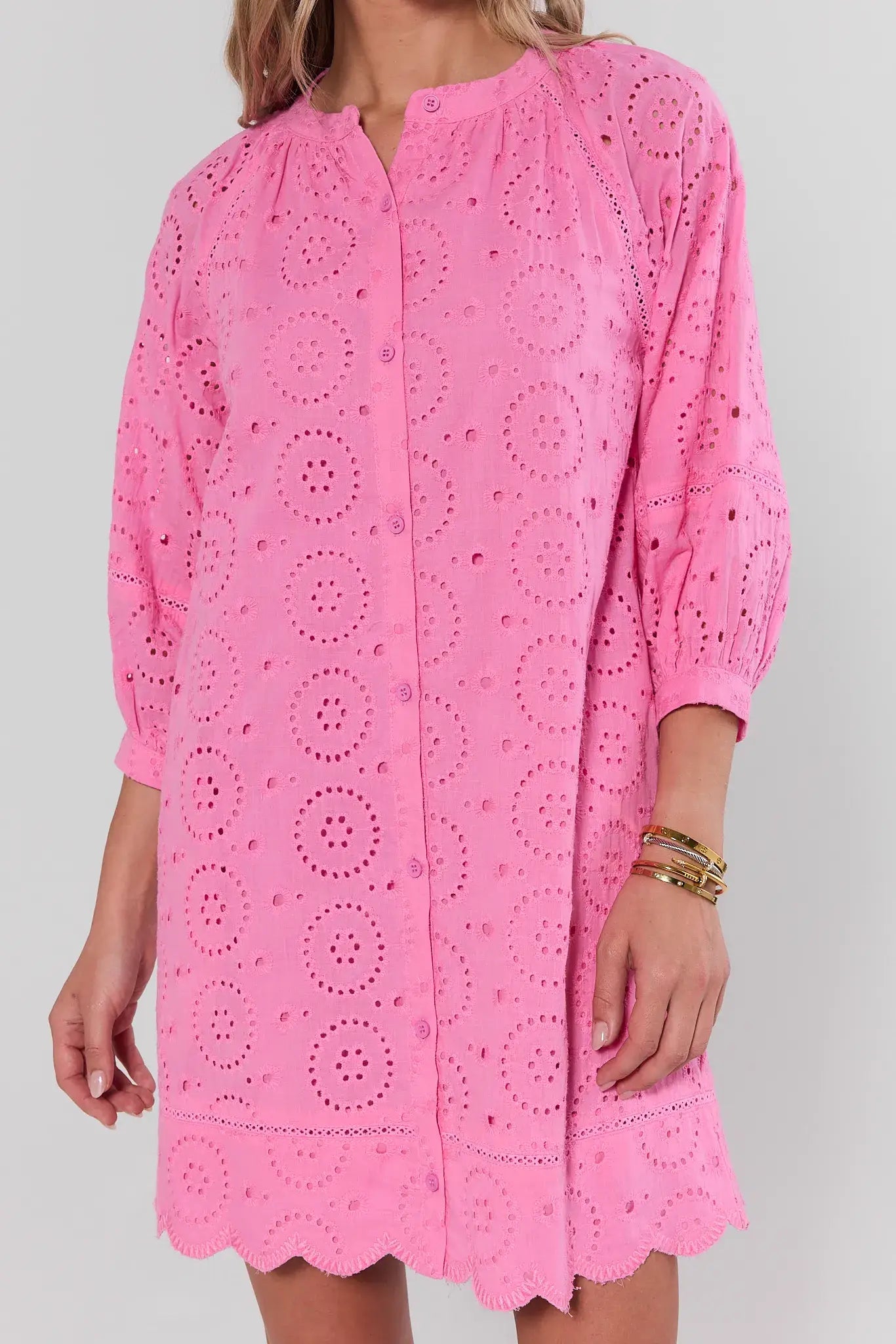 Pink lace dress worn by a person on a white background close up