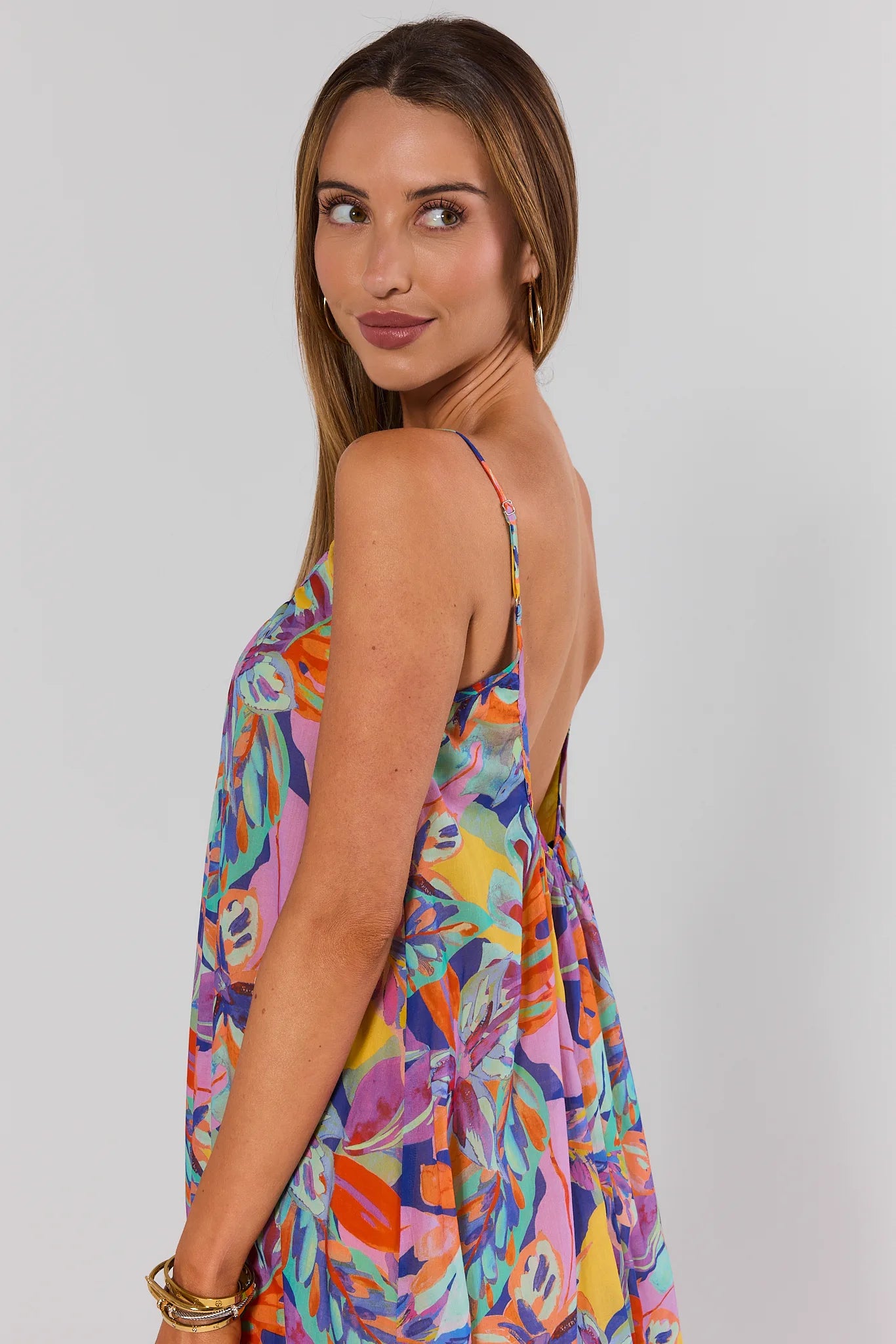 Woman wearing a colorful patterned dress on a plain background side