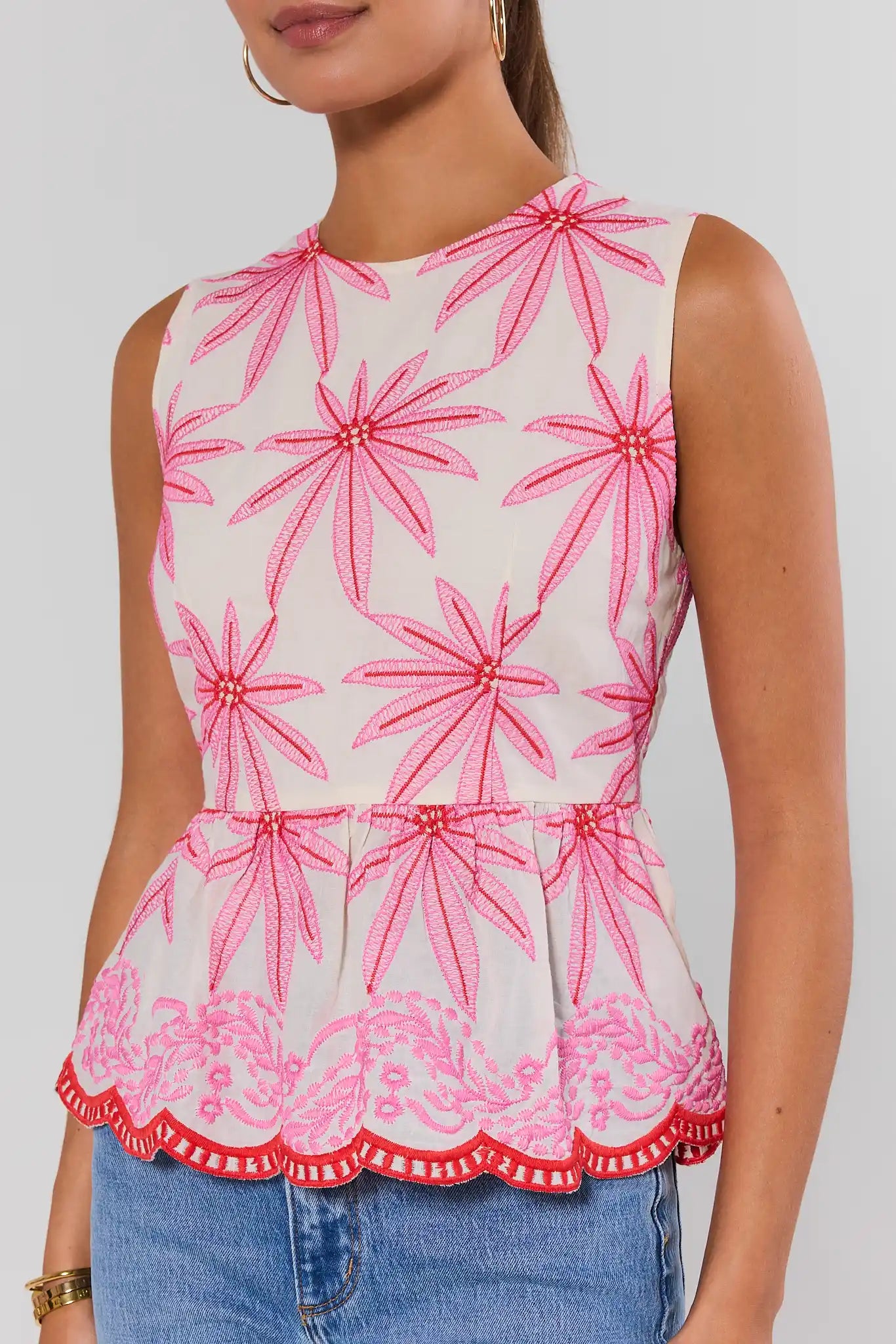Woman wearing a sleeveless top with pink floral pattern on a plain background close up