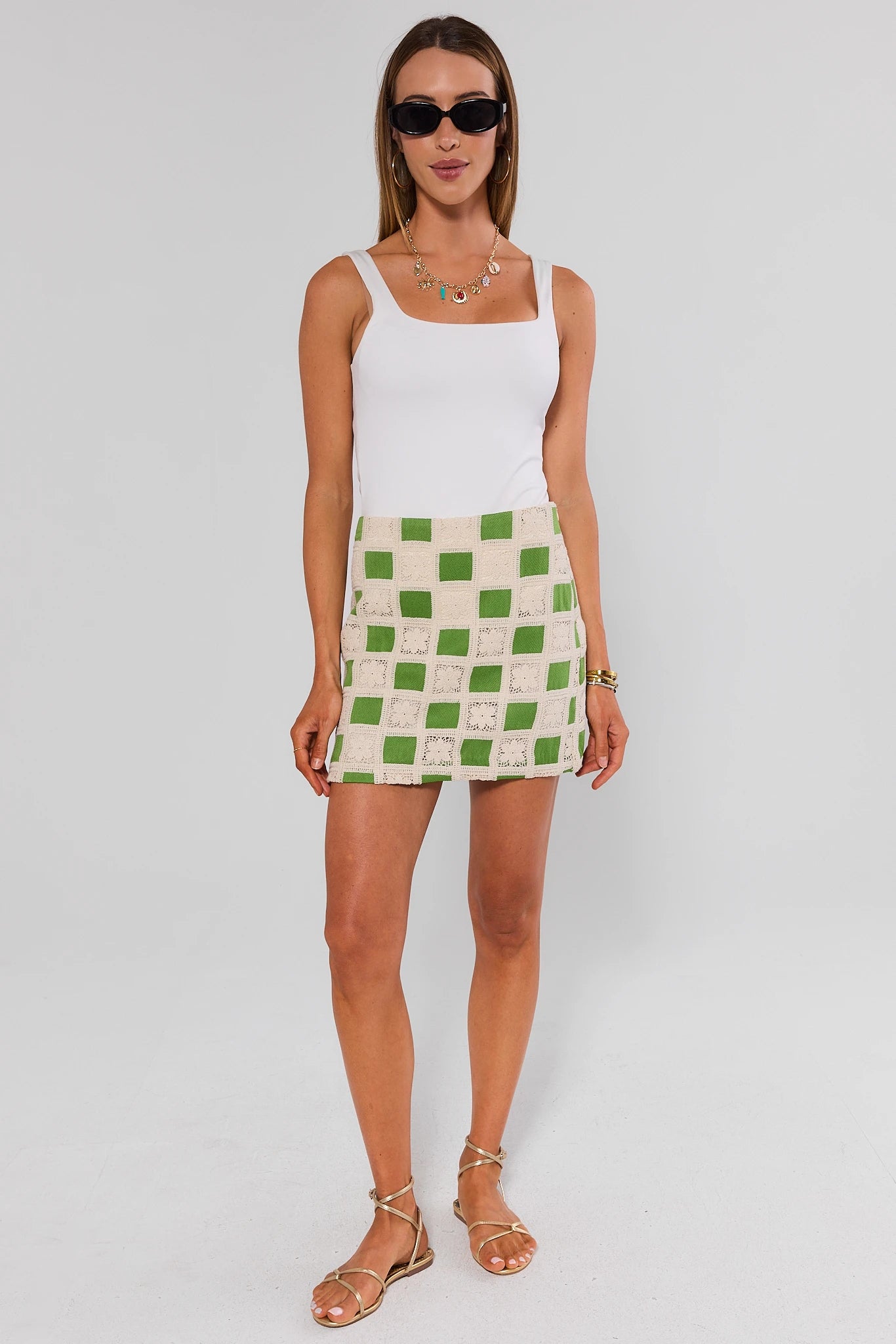 Woman wearing a white tank top and green checkered skirt on a white background