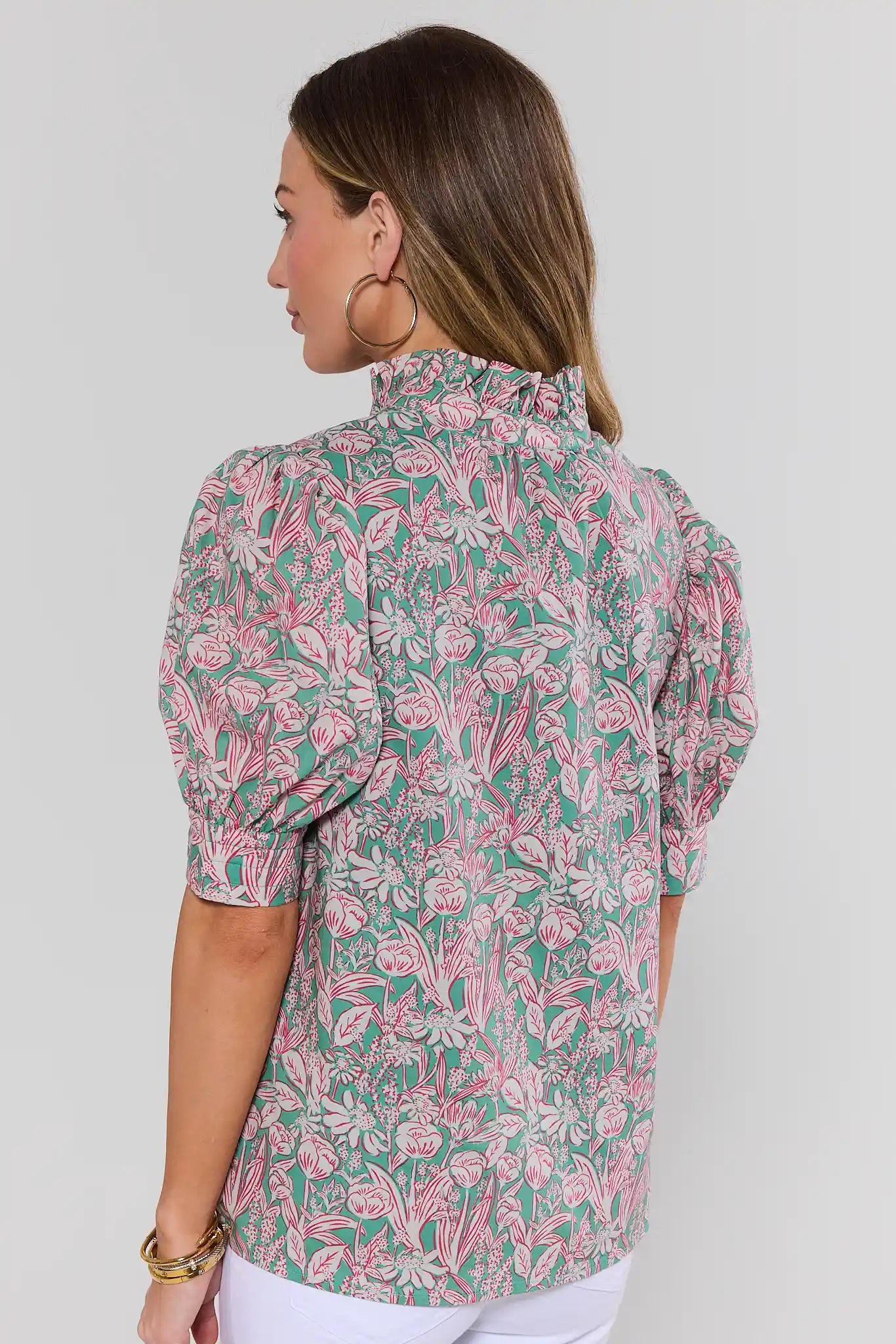 Woman standing wearing a floral patterned shirt against a plain background