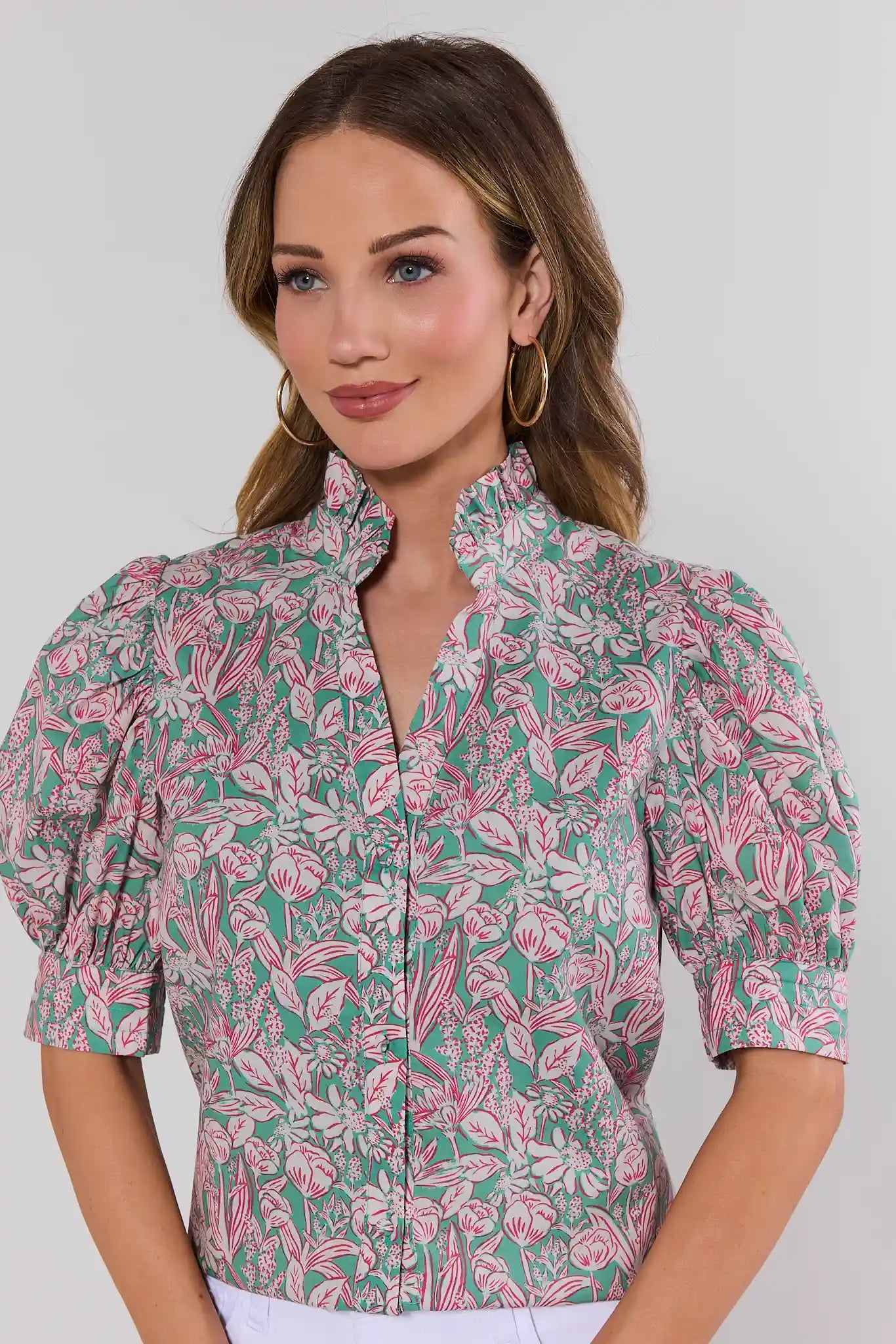 Woman wearing a floral patterned blouse against a plain background close up