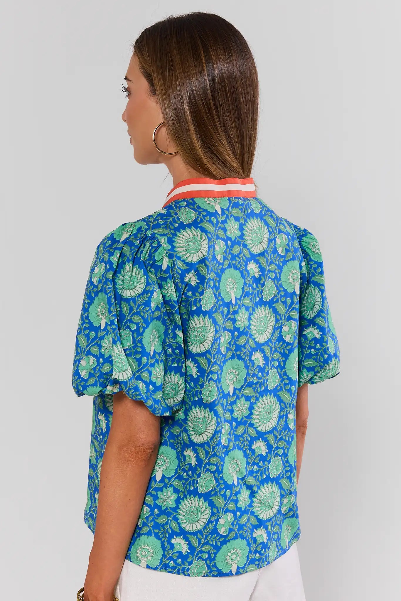 Woman wearing a blue floral blouse with a plain background standing