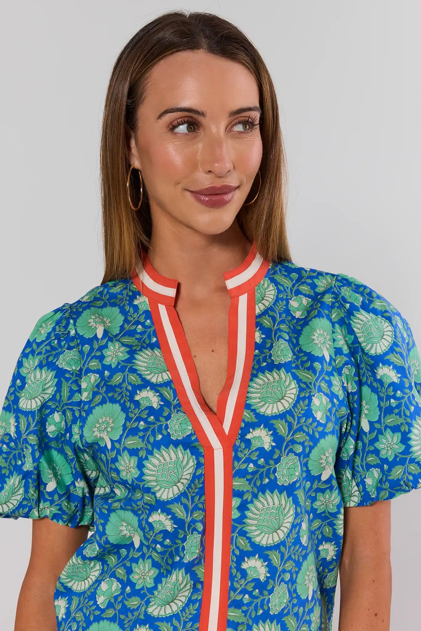 Woman wearing a blue floral top with a white background close up