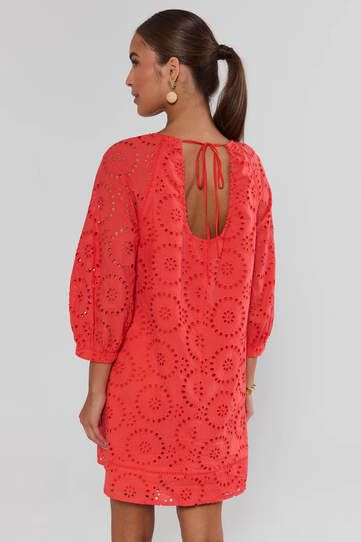 Woman back wearing a red lace dress against a gray background