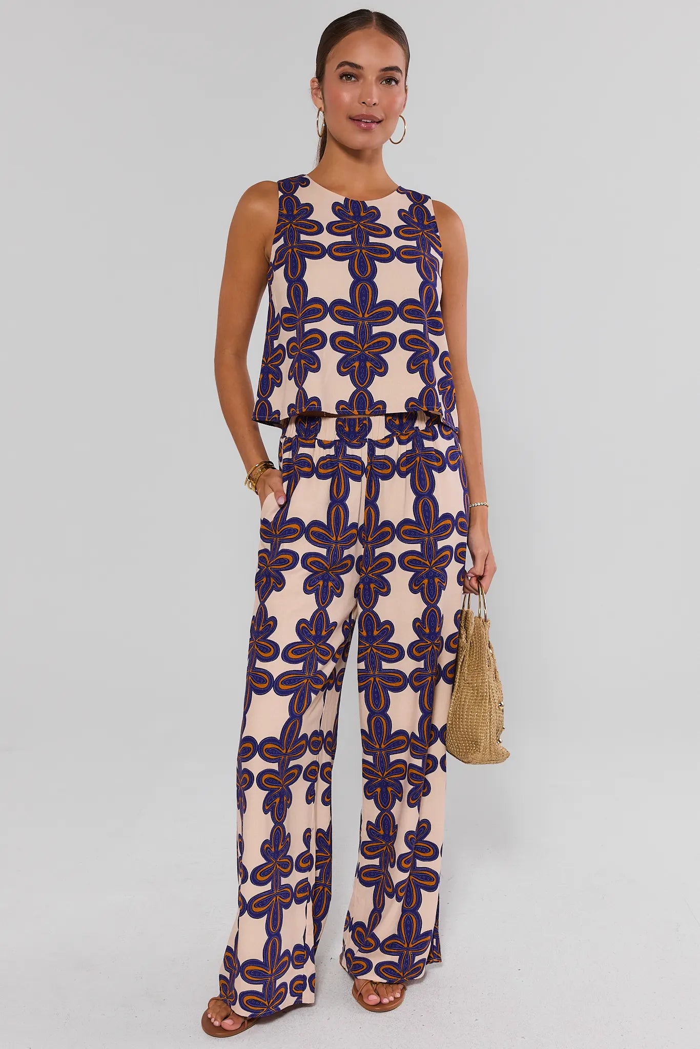 Woman wearing a patterned jumpsuit on a plain background standing