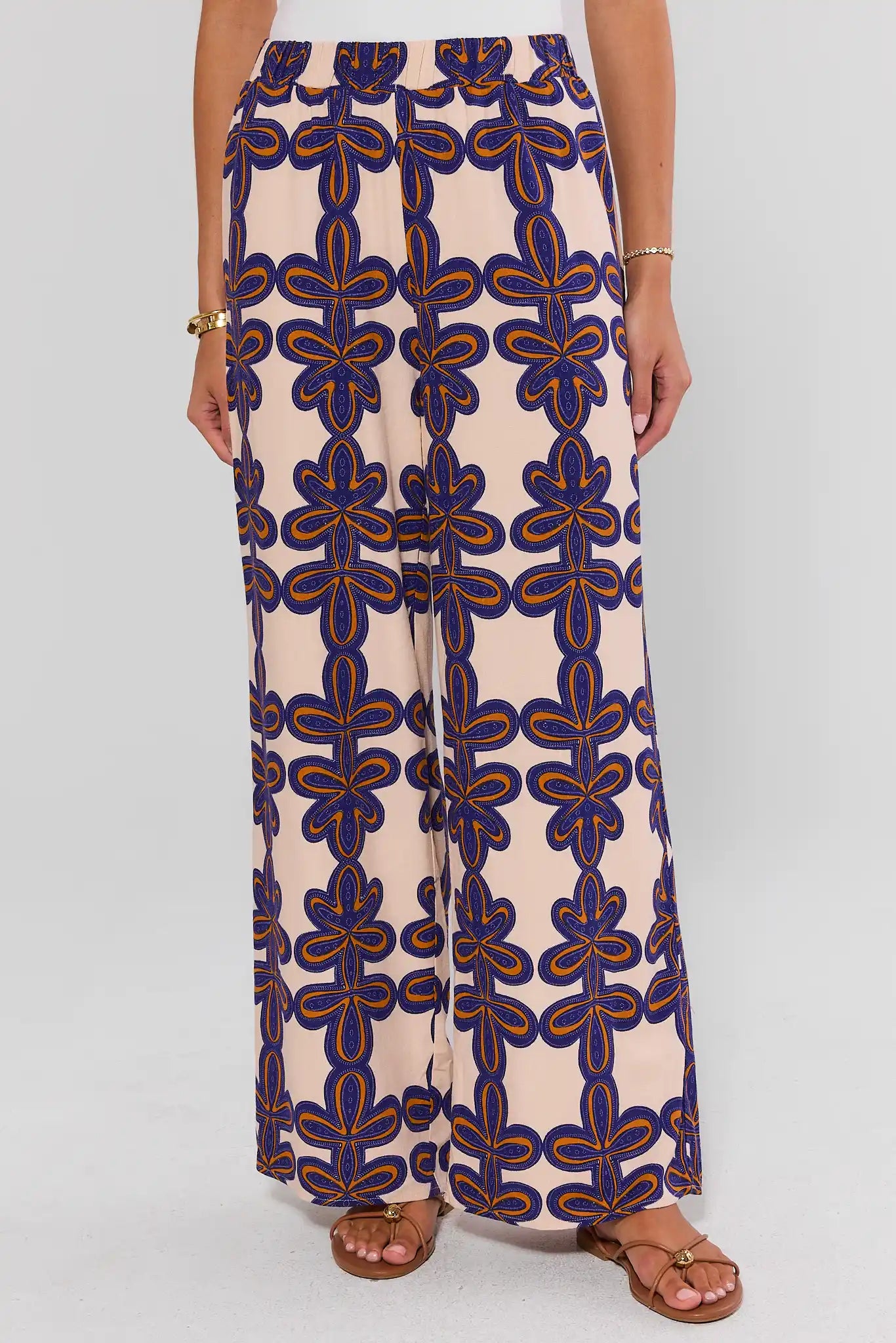 Person wearing a pair of wide-leg pants with a blue and orange pattern on a white background