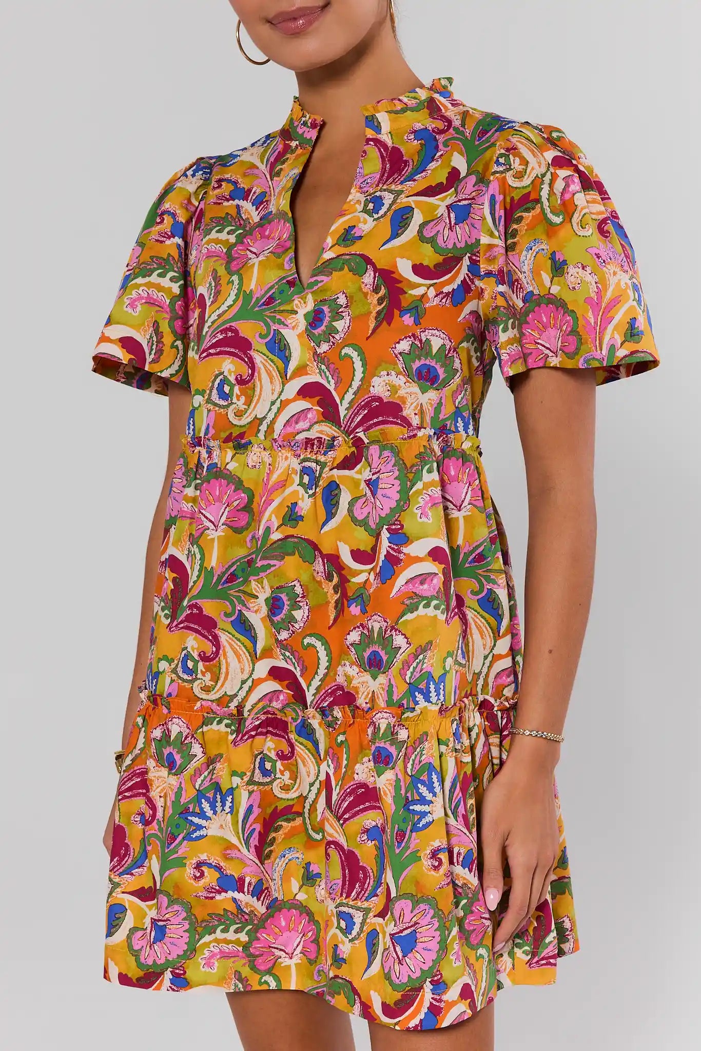 Woman wearing a colorful patterned dress on a plain background close up