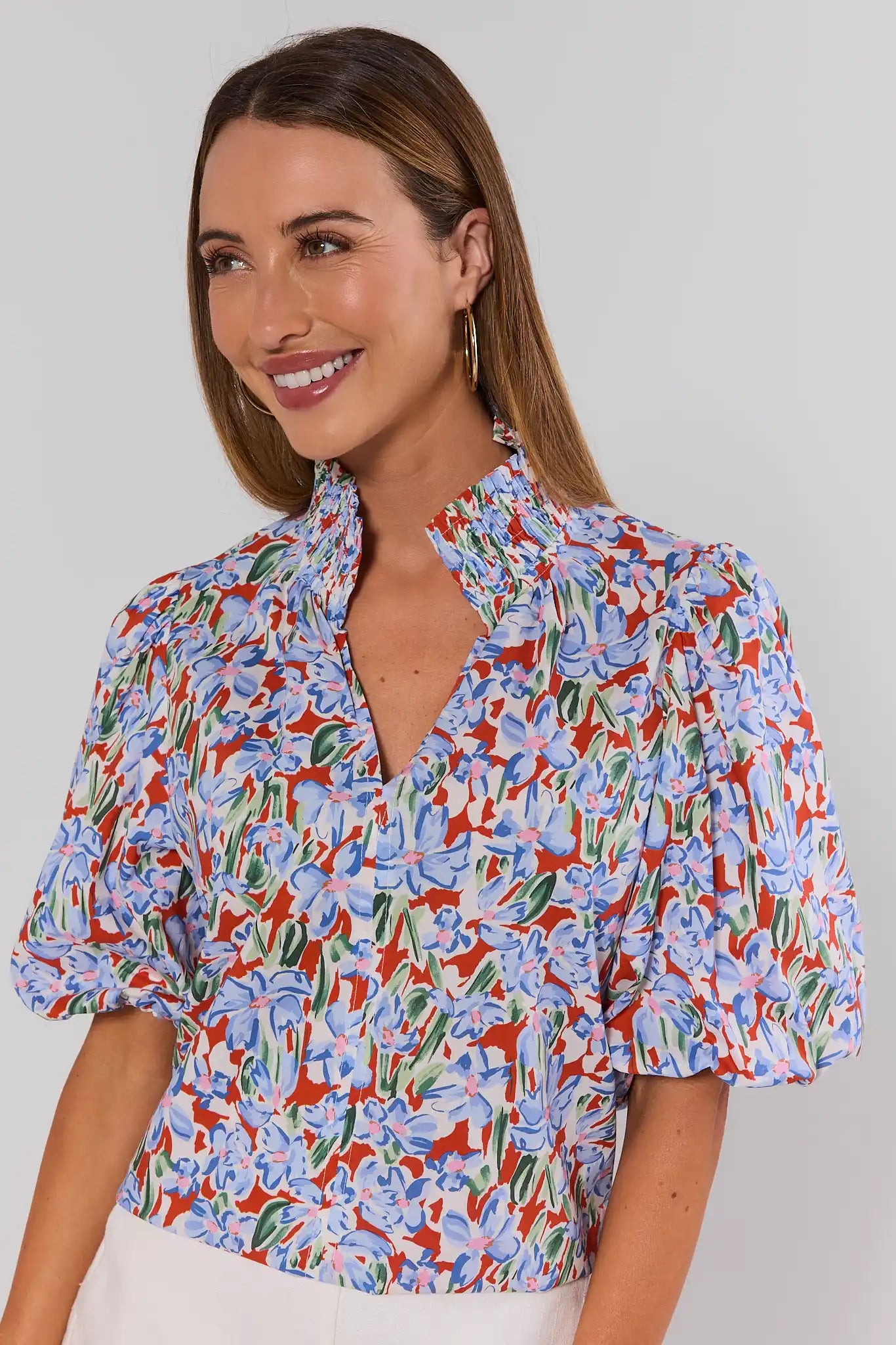 Woman wearing a colorful floral blouse against a plain background close up