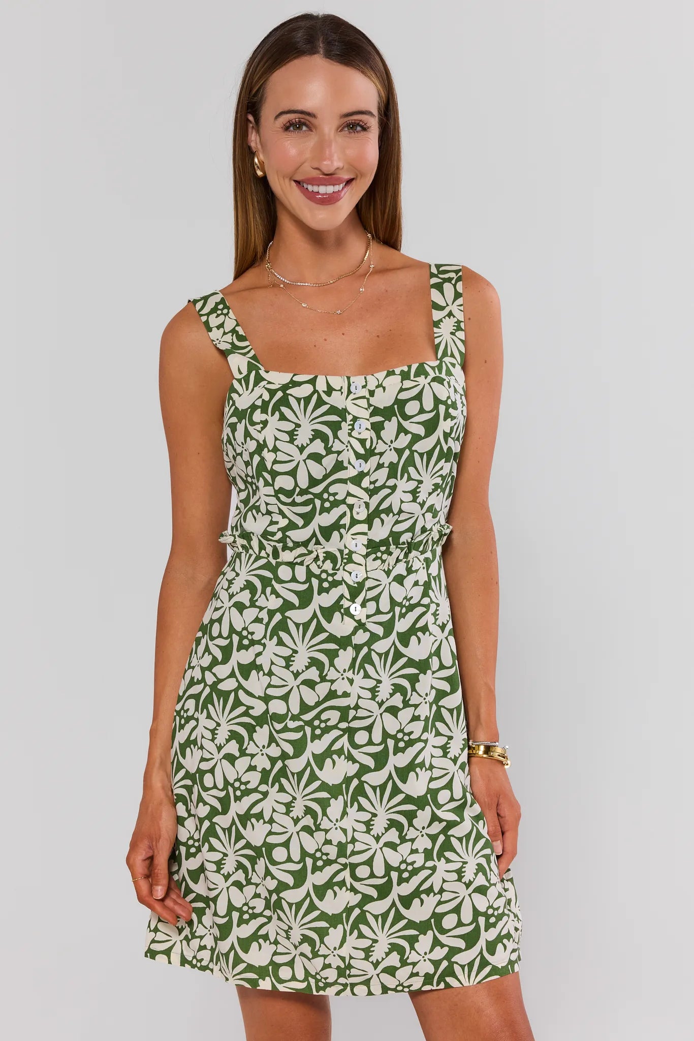 Woman wearing a green floral dress against a plain background