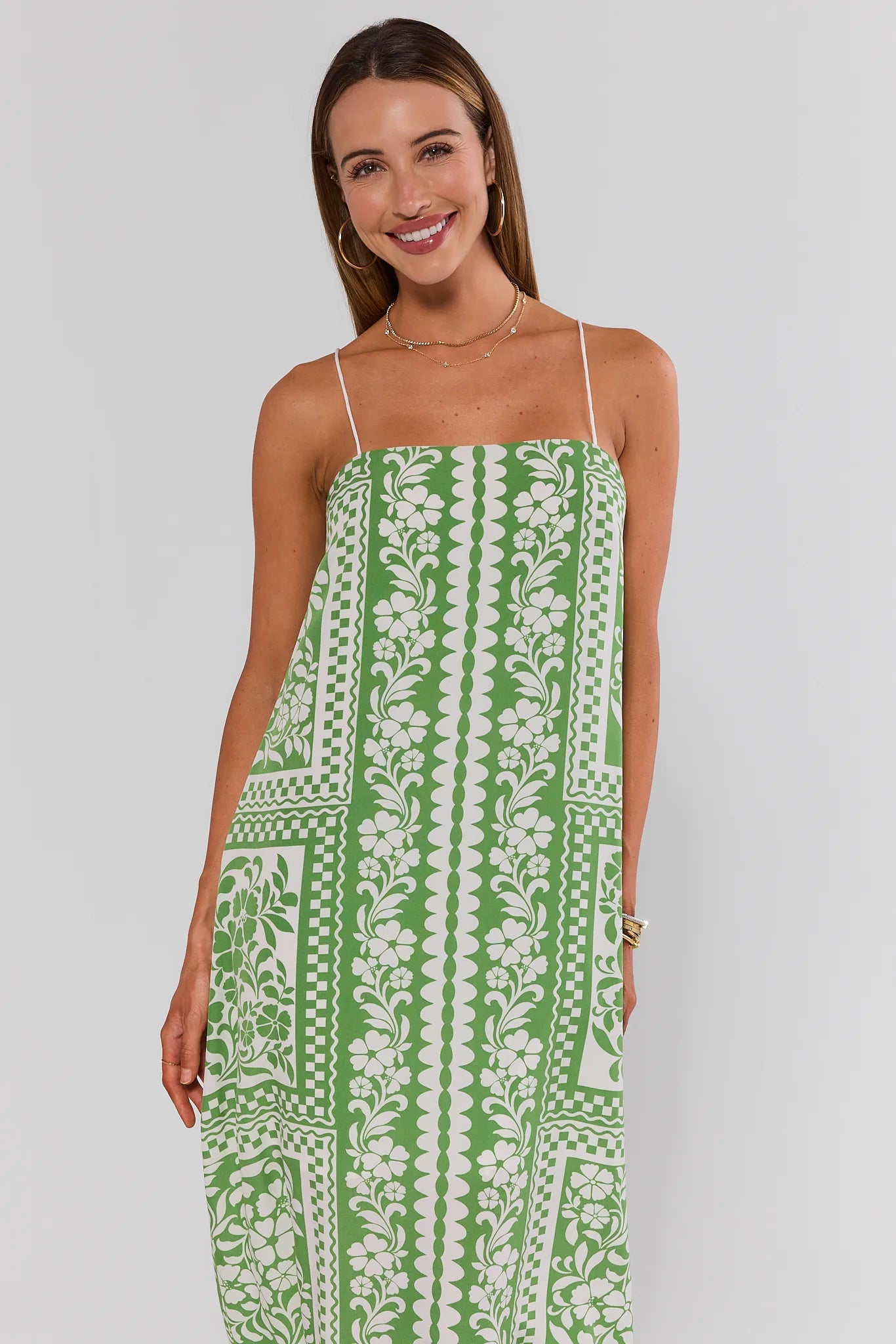 Woman wearing a green and white patterned dress on a plain background