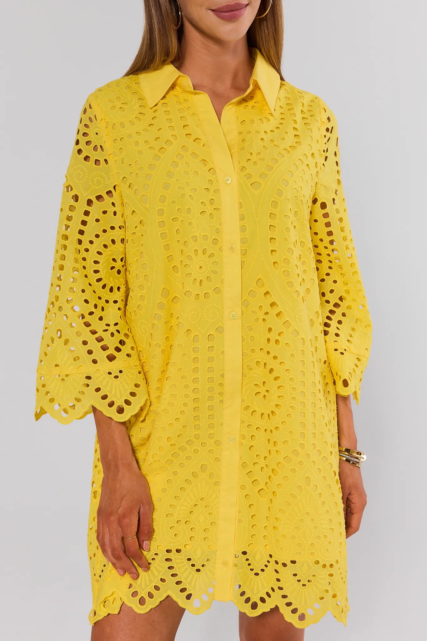 Yellow lace dress worn by a person on a plain background close up