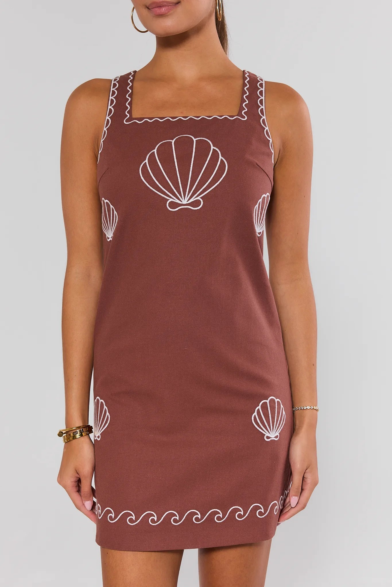 Brown dress with white shell patterns on a plain background standing