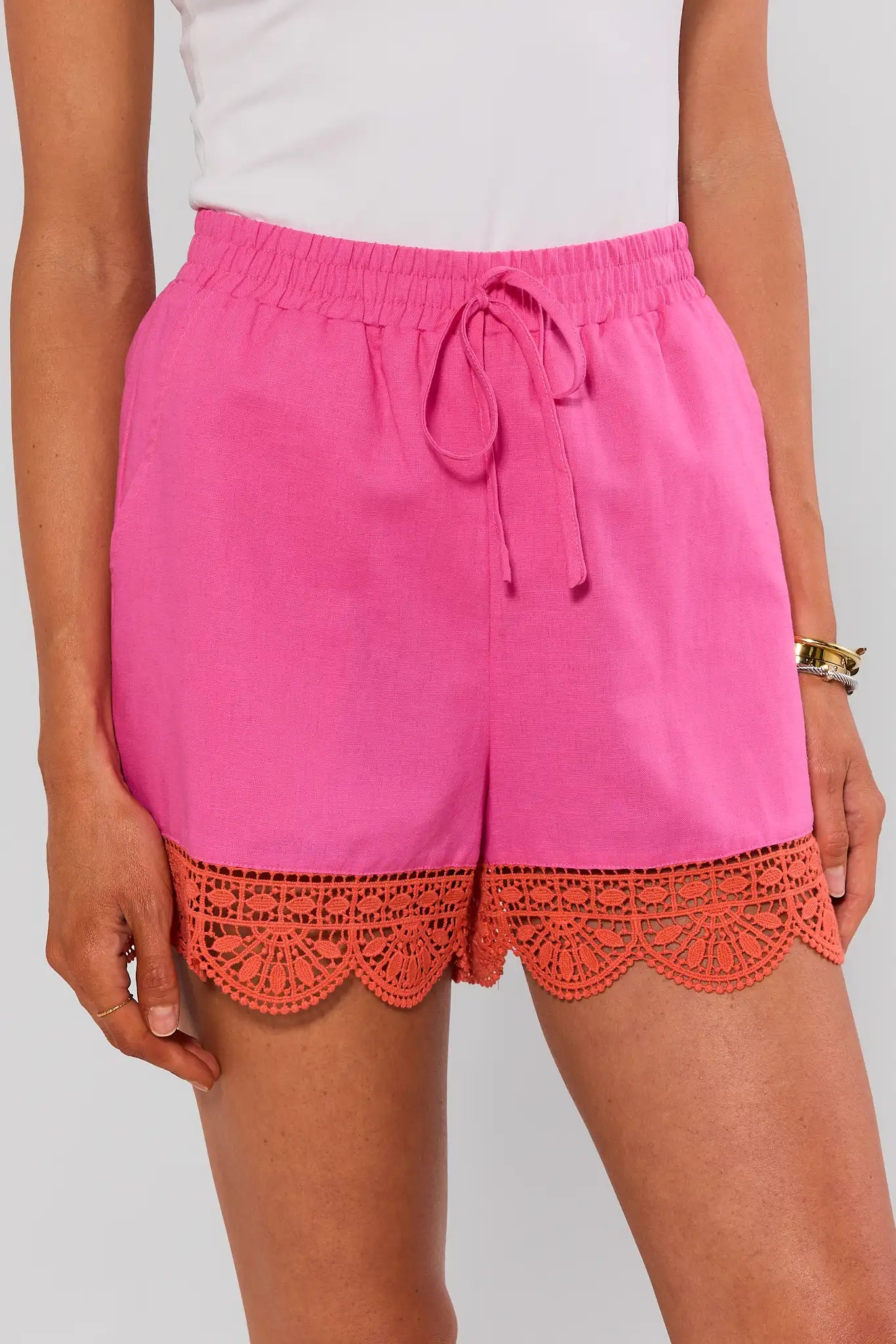 Pink shorts with orange lace trim worn by a person on a plain background