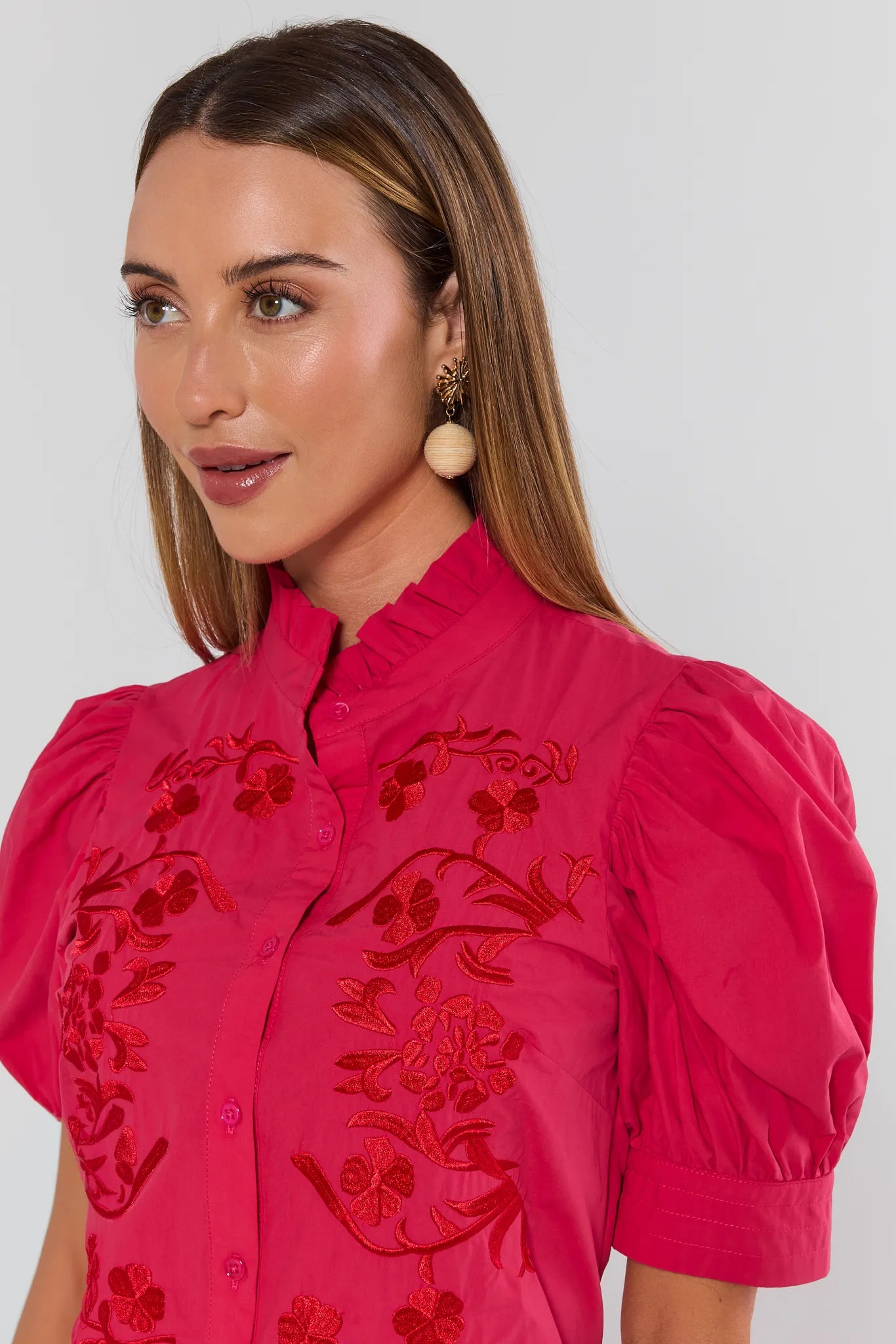 close up Woman wearing a pink blouse with red floral embroidery on a white background