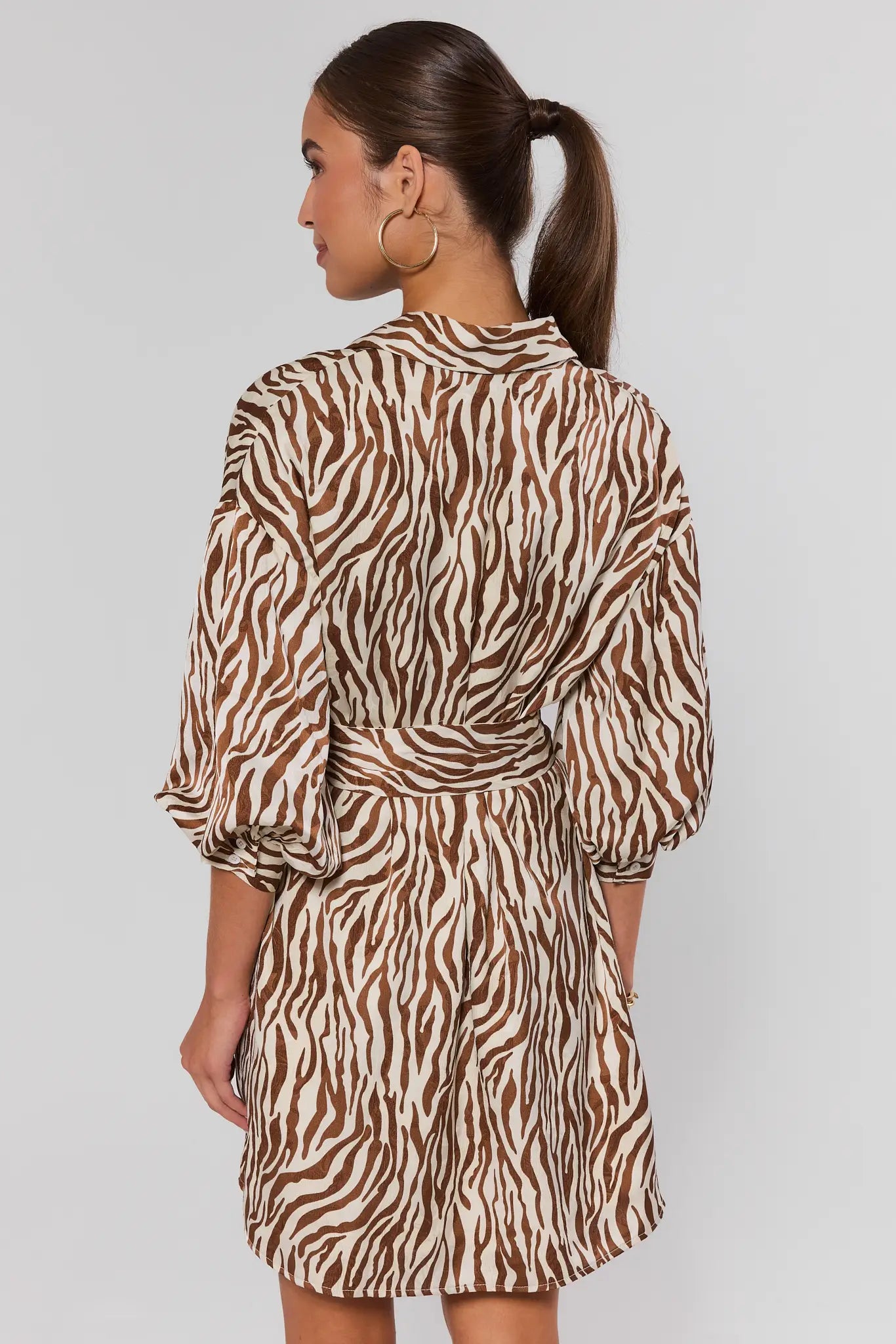 Woman standing wearing a zebra print dress against a plain background