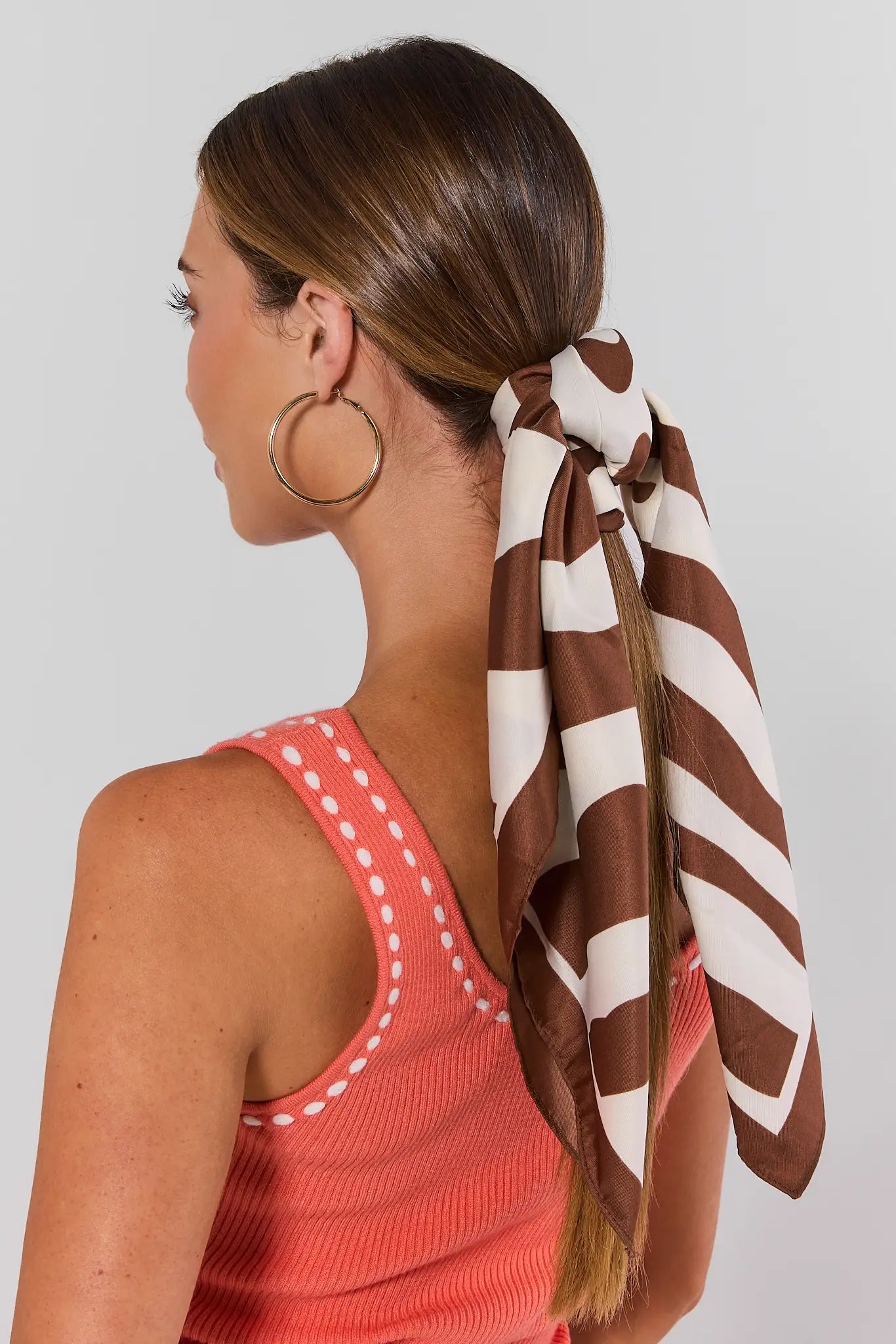 Woman wearing a brown and white striped headscarf on a plain background