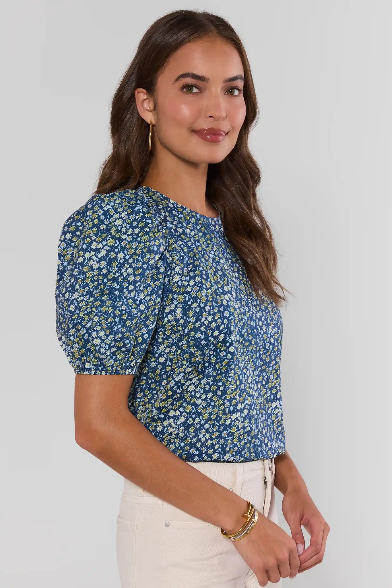 Woman wearing a blue floral top against a white background standing