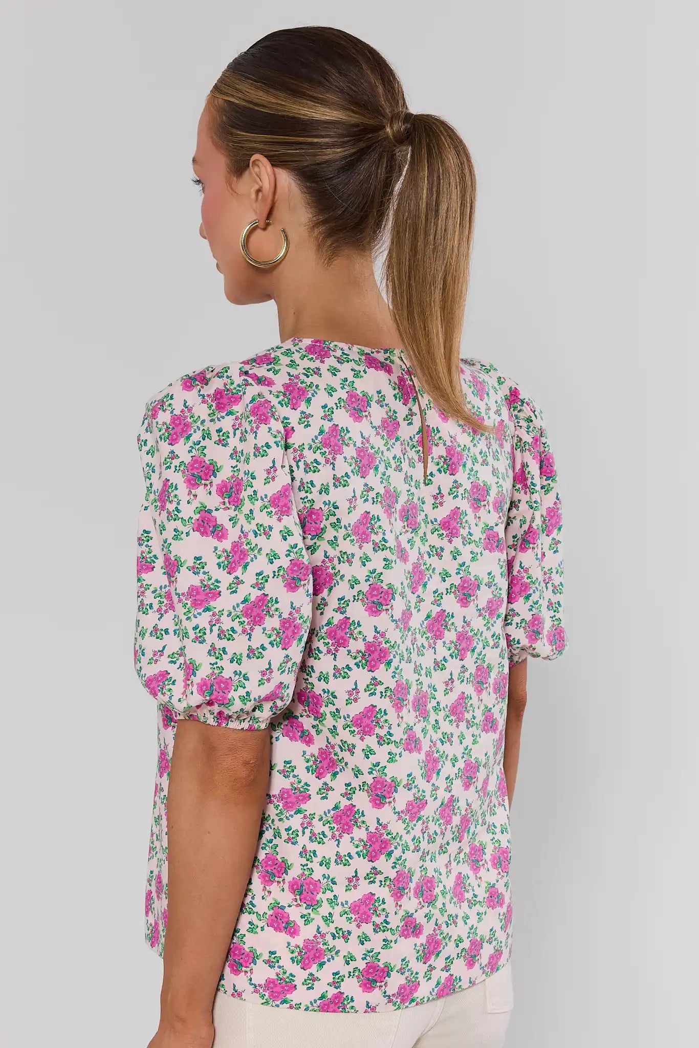 Woman wearing a floral blouse with a plain background standing
