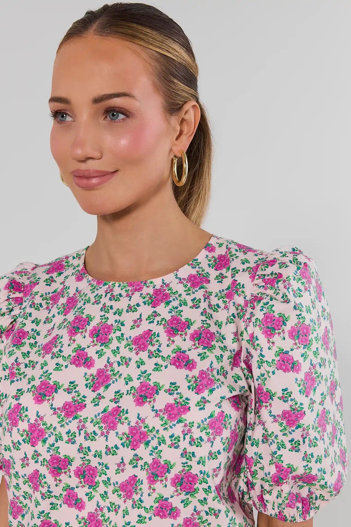 Woman wearing a floral blouse with a plain background close up