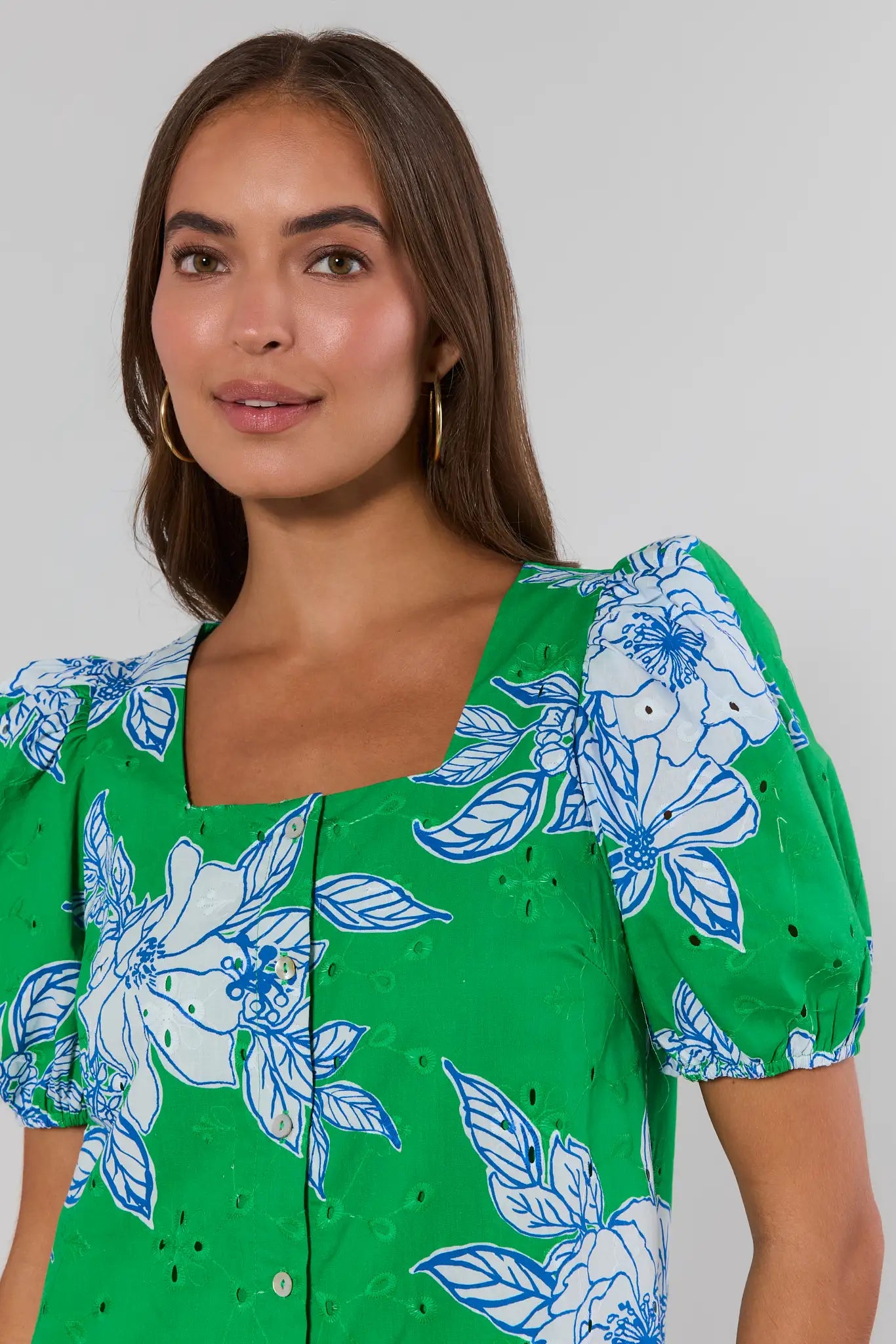 Woman wearing a green floral dress against a plain background close up