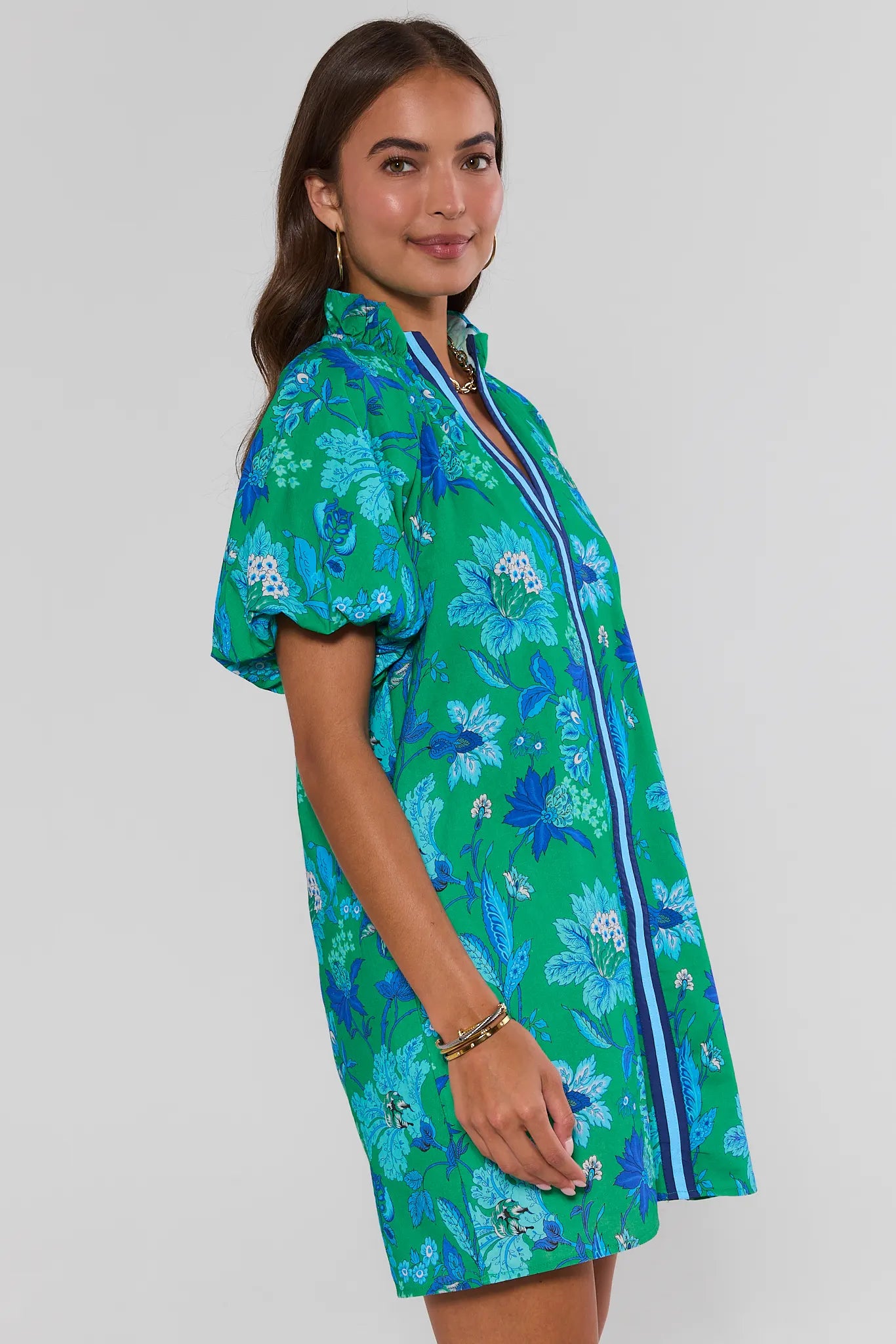 Woman wearing a green floral dress with a white background side