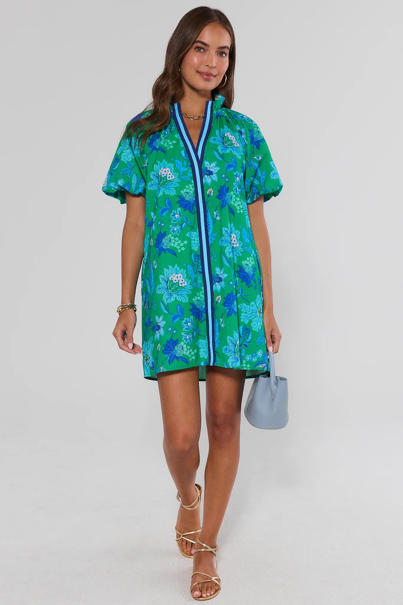 Woman wearing a green floral dress with a white background walking