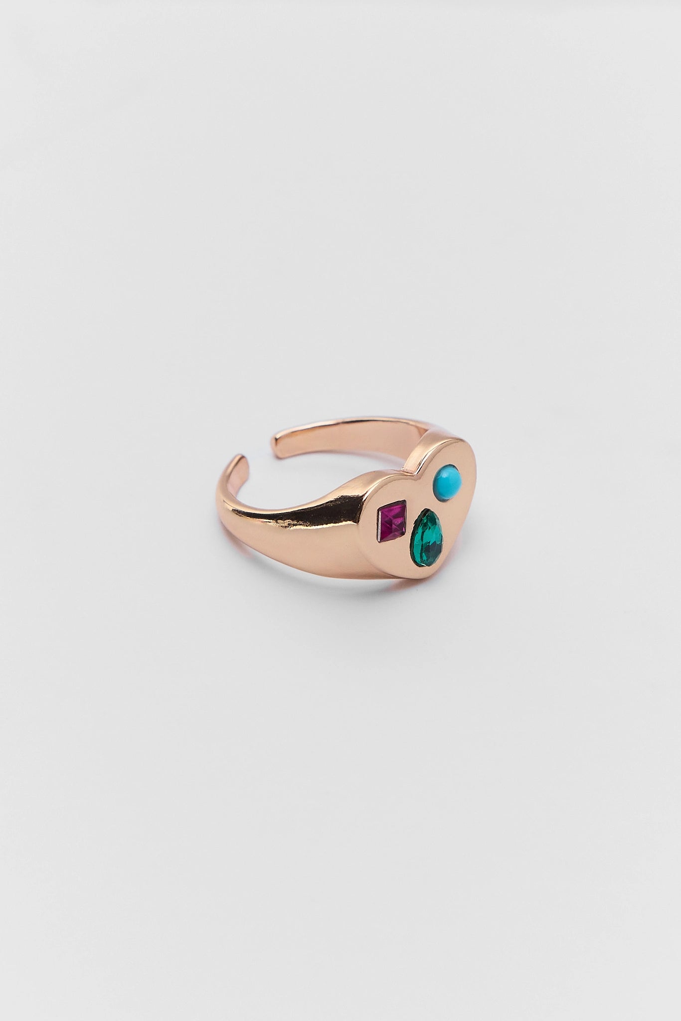 Rose gold ring with gemstones on a light gray background 