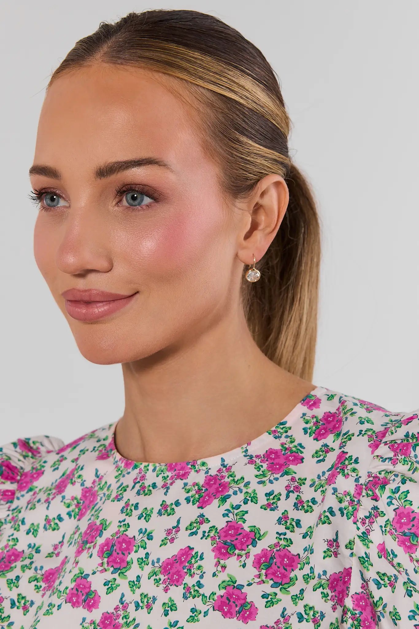 Woman wearing a floral dress and earrings with a plain background