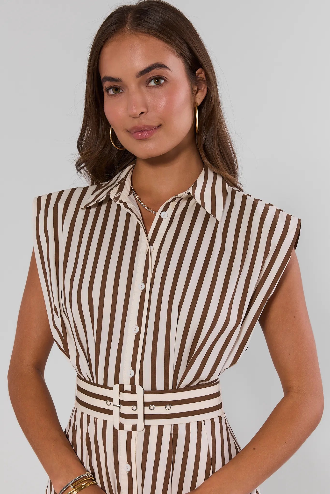 Woman wearing a brown and white striped dress against a plain background close up