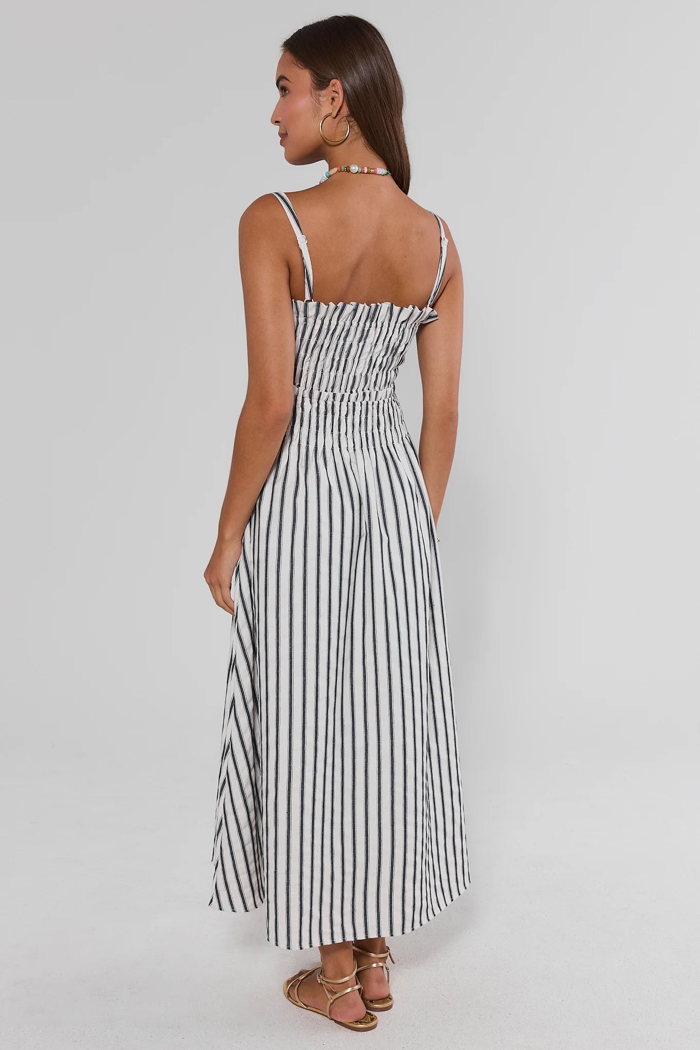 Woman wearing a black and white striped dress on a gray background stand